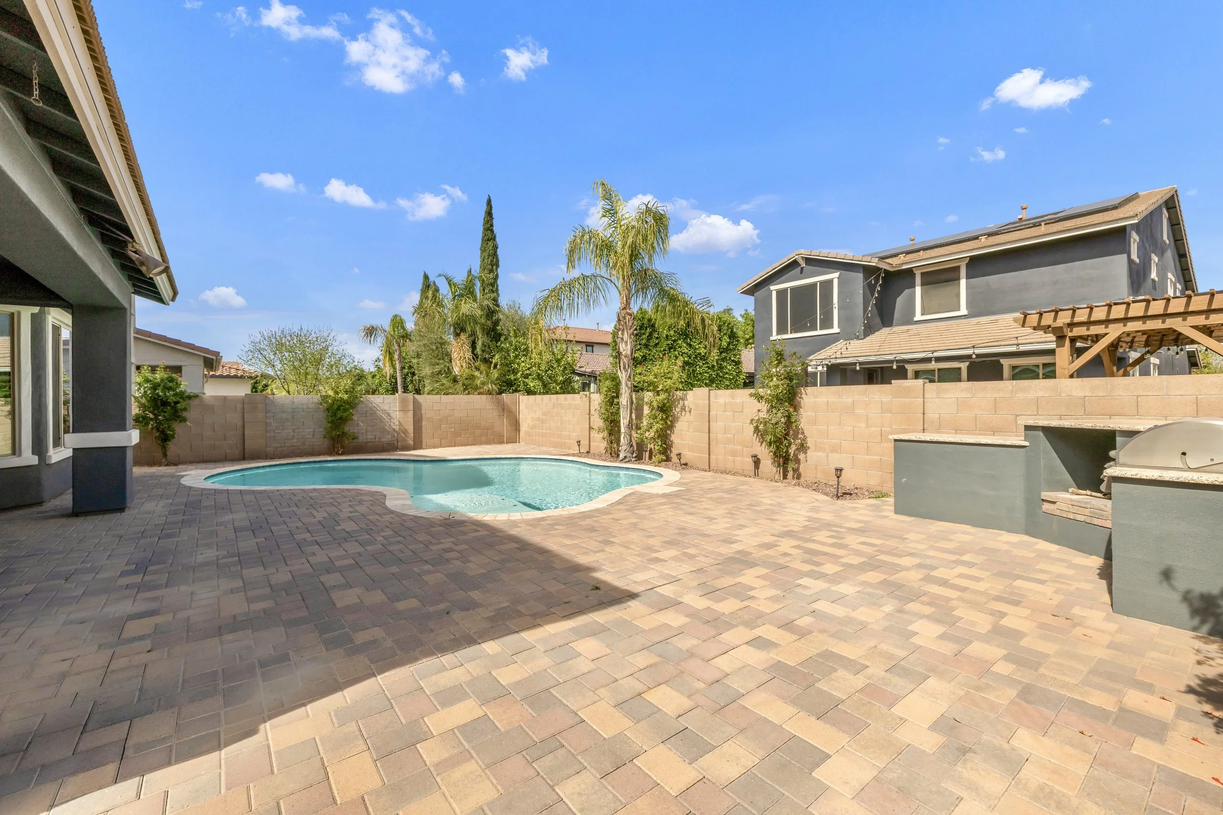 This Gilbert, AZ backyard features a pool, spacious patio, and outdoor grill, showcasing excellent real estate photography in Morrison Ranch neighborhood.