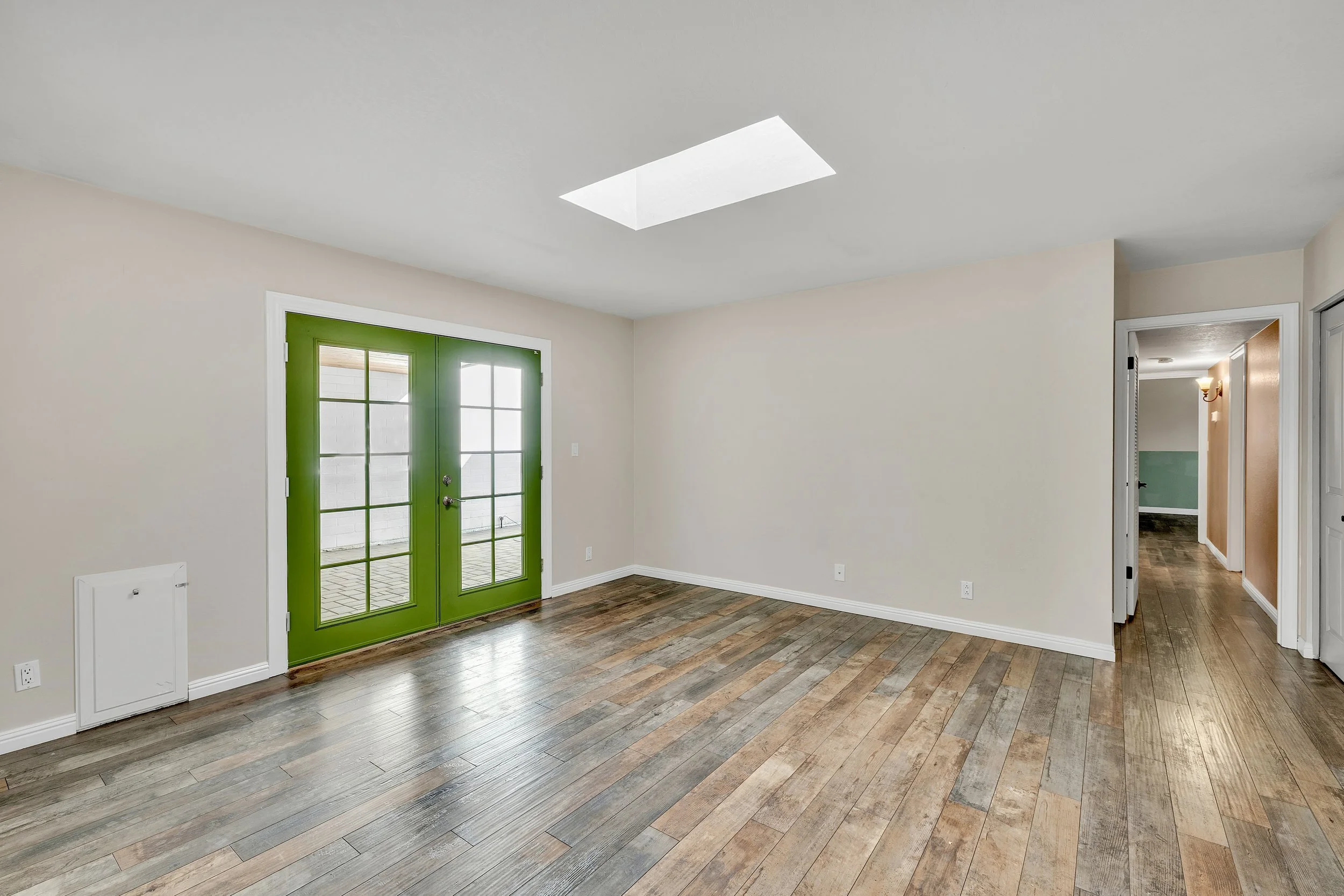 This spacious empty room in Tempe, AZ features vibrant green doors and natural light, captured perfectly with expert real estate photography to highlight its potential.