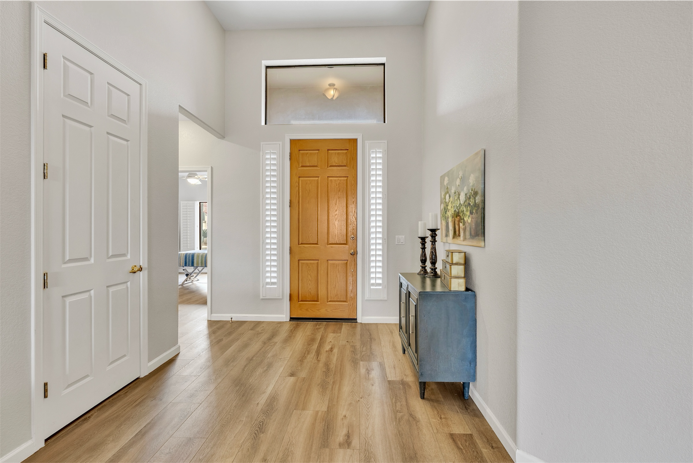 This bright interior entryway in Goodyear, AZ features wood flooring and tasteful decor, captured with professional real estate photography to highlight its inviting atmosphere.