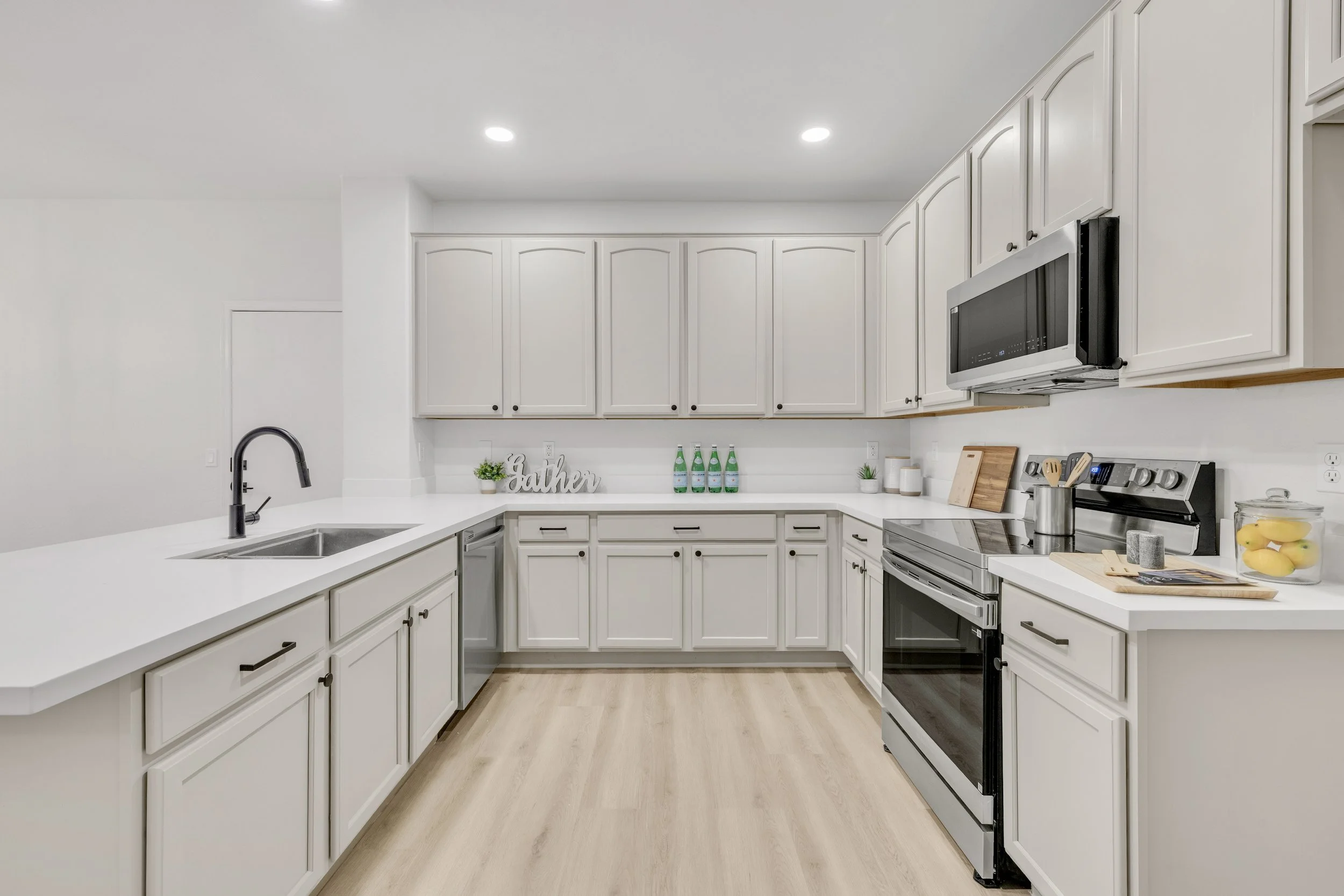 Bright modern kitchen with white cabinetry and stainless steel appliances captured in Gilbert, AZ, showcasing high-quality real estate photography for appealing home listings.