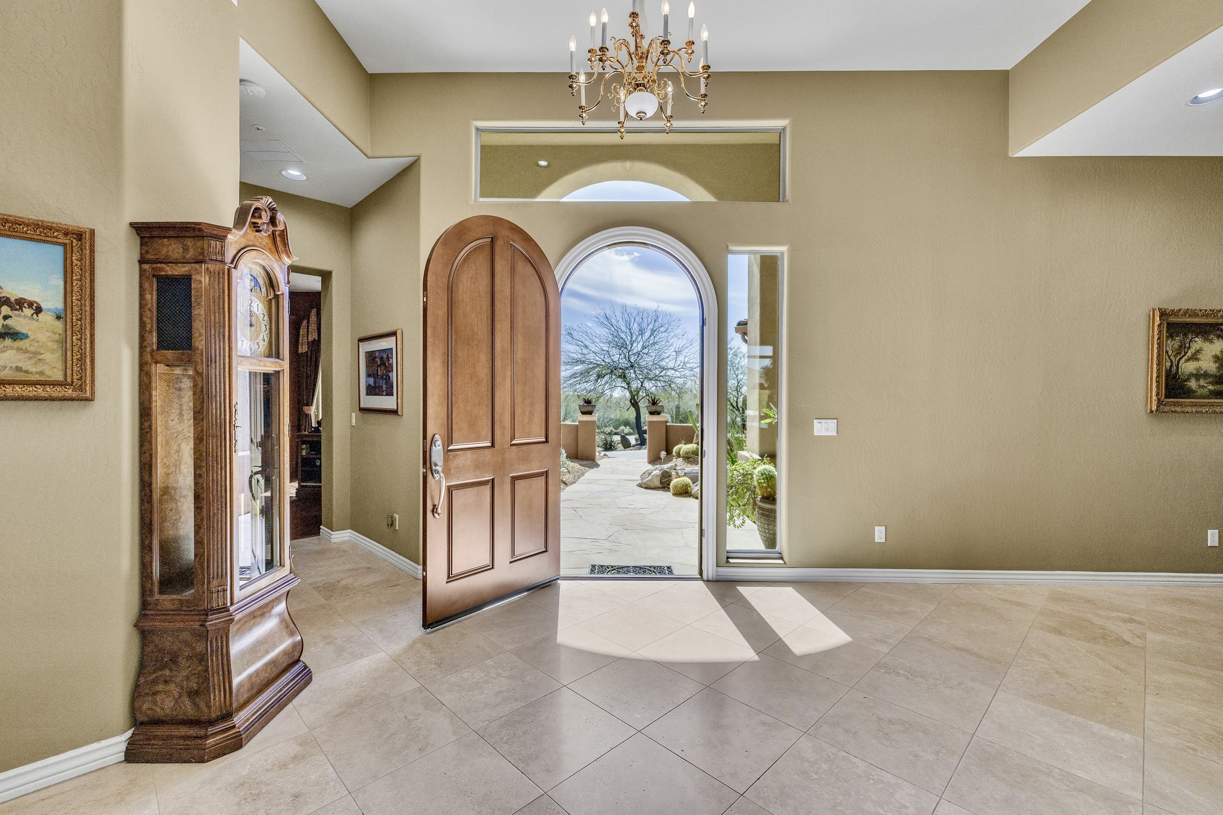 Bright foyer with an open wooden front door and tile flooring captured in real estate photography in Scottsdale, AZ.