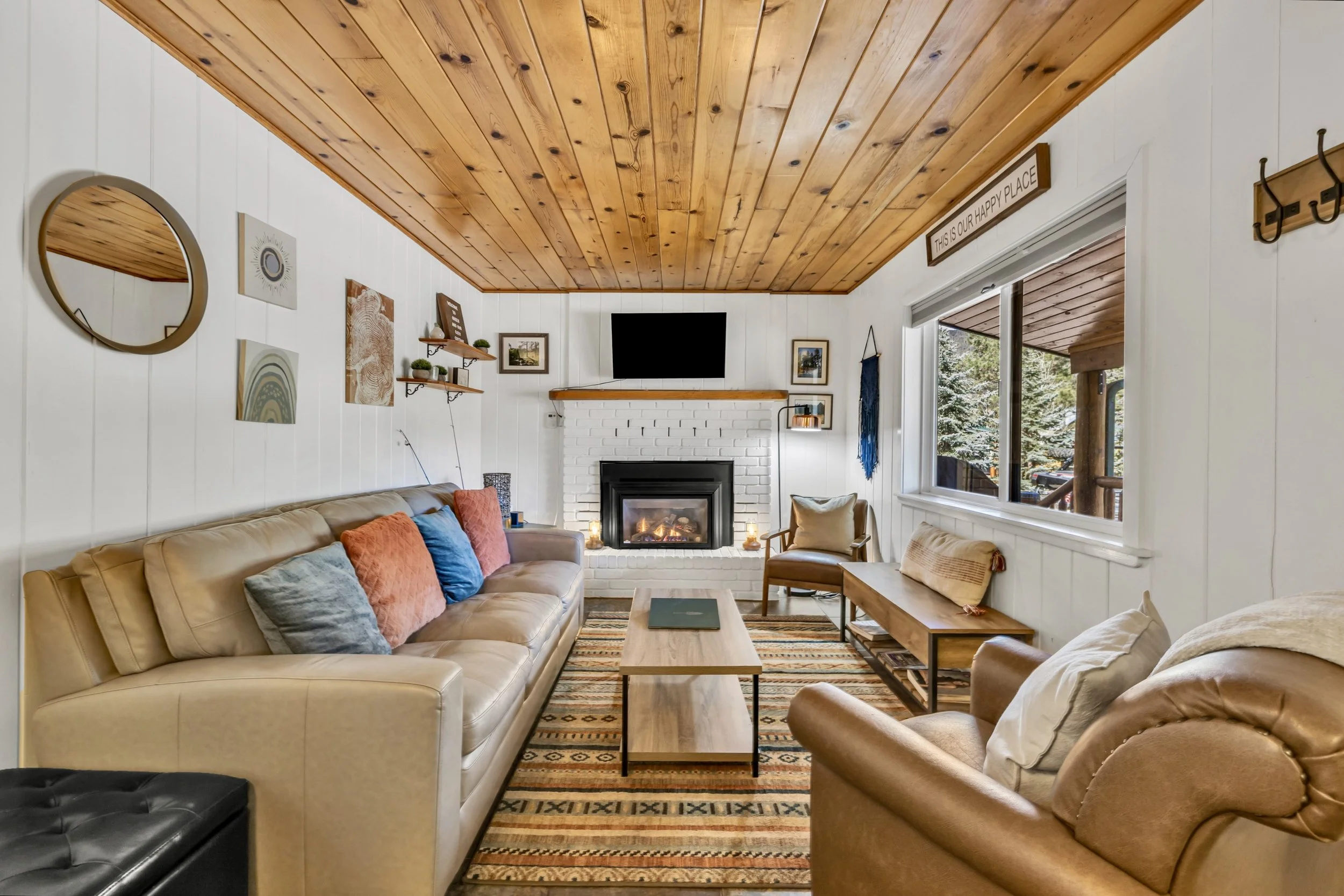 Cozy rustic living room with a fireplace and large window, showcasing charming real estate photography in Greer, AZ.