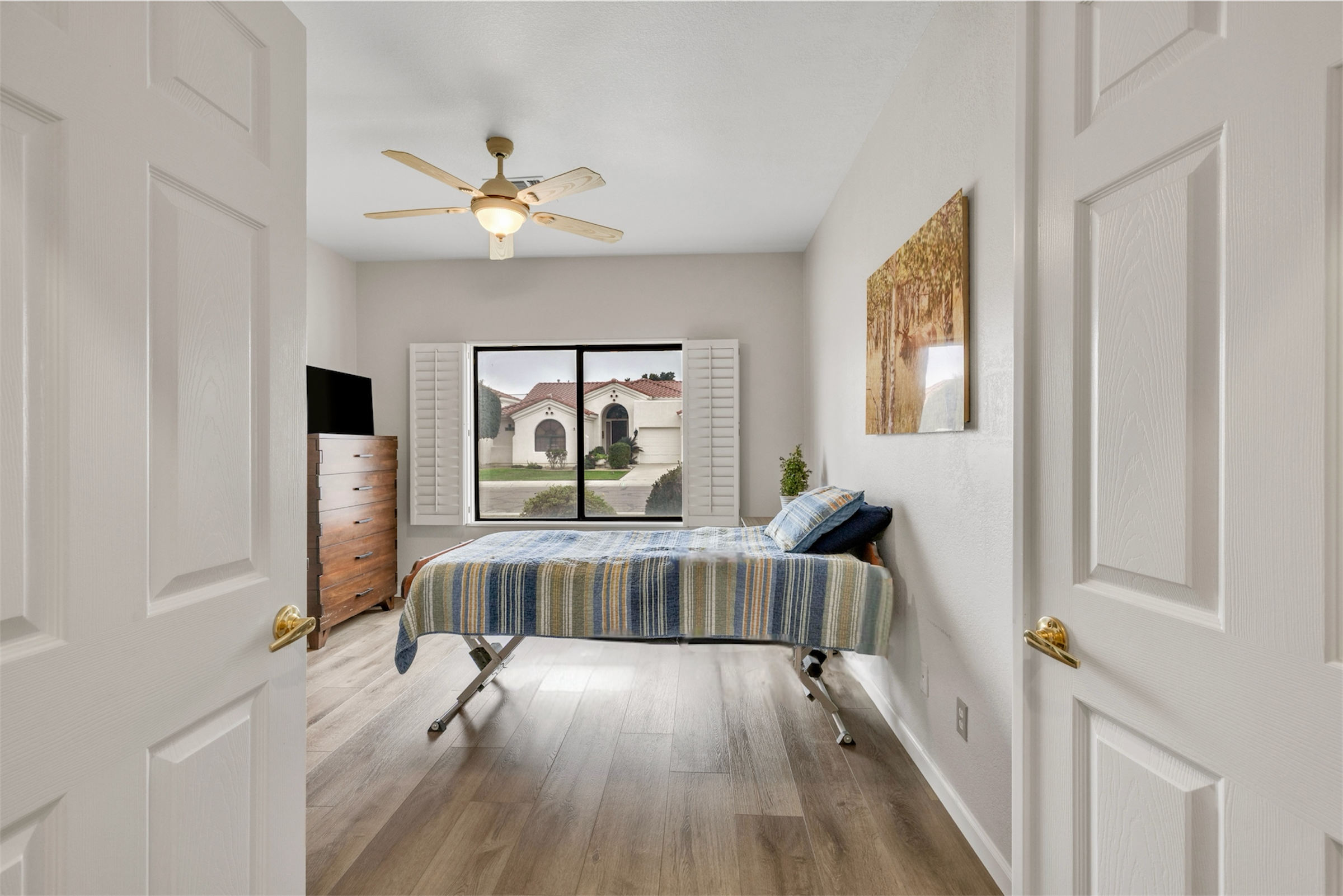 This bedroom in Goodyear, AZ features a window view with plantation shutters and modern flooring, captured with professional real estate photography.