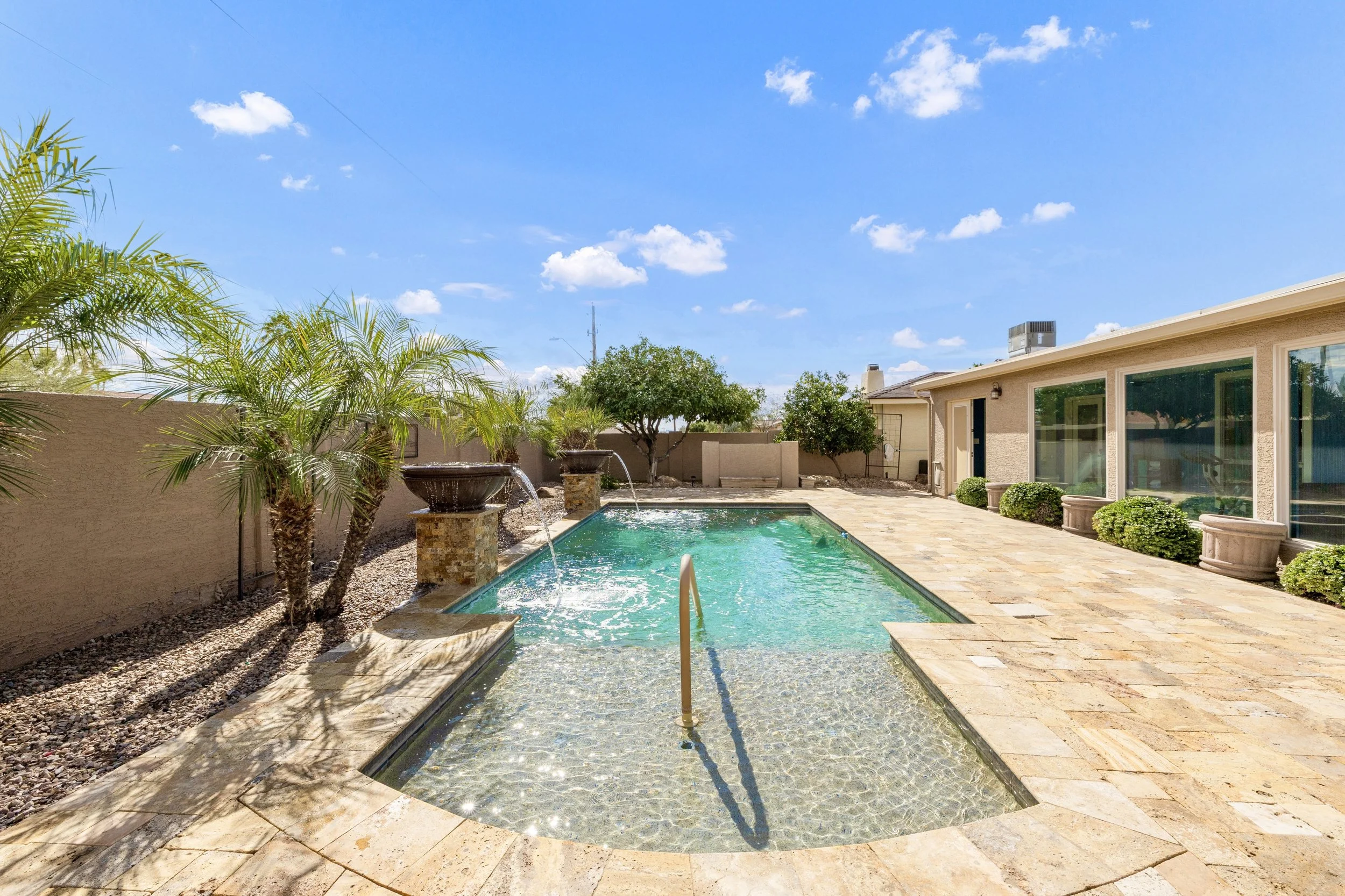 Beautiful backyard with a swimming pool and palm trees in Sun Lakes, AZ, captured with professional real estate photography showcasing the inviting outdoor space.