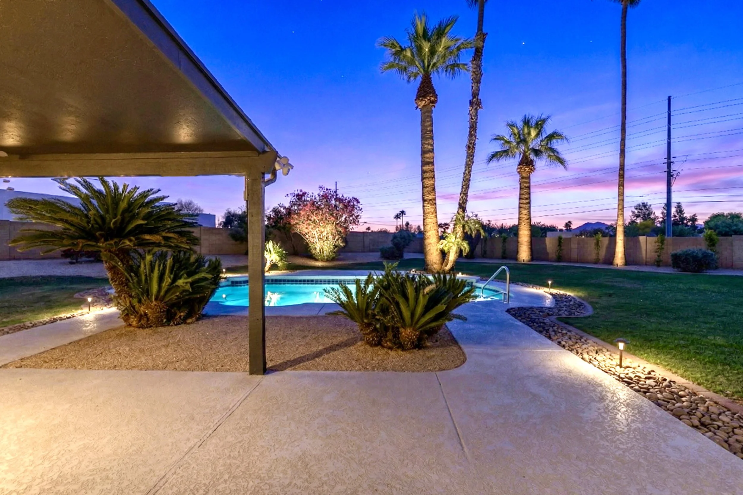 Twilight backyard with illuminated pool and palm trees in Scottsdale, AZ, captured in this real estate photography perfect for showcasing outdoor living spaces.