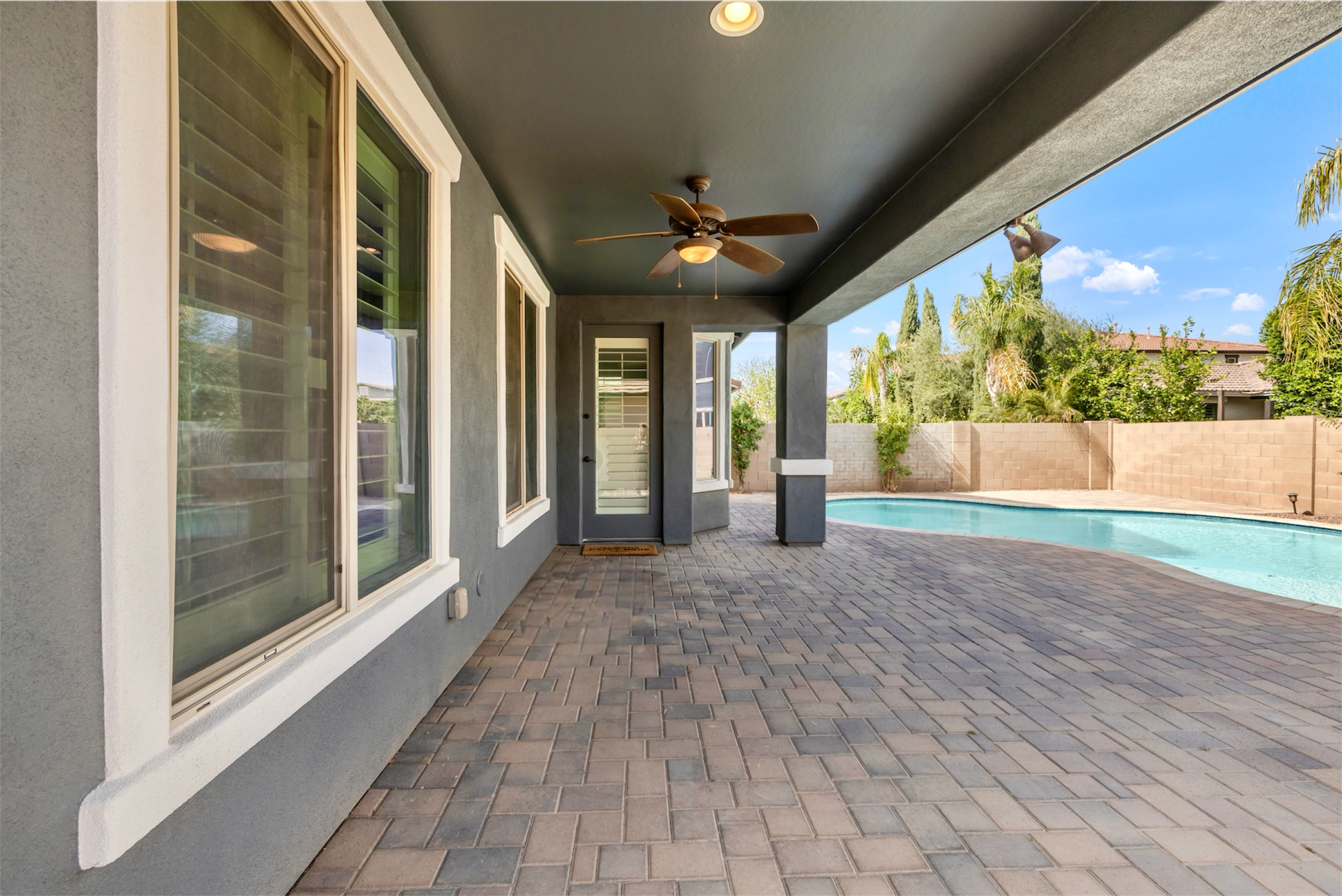 Covered patio with ceiling fan overlooking a backyard pool in Gilbert, AZ, captured in quality real estate photography in Morrison Ranch neighborhood.