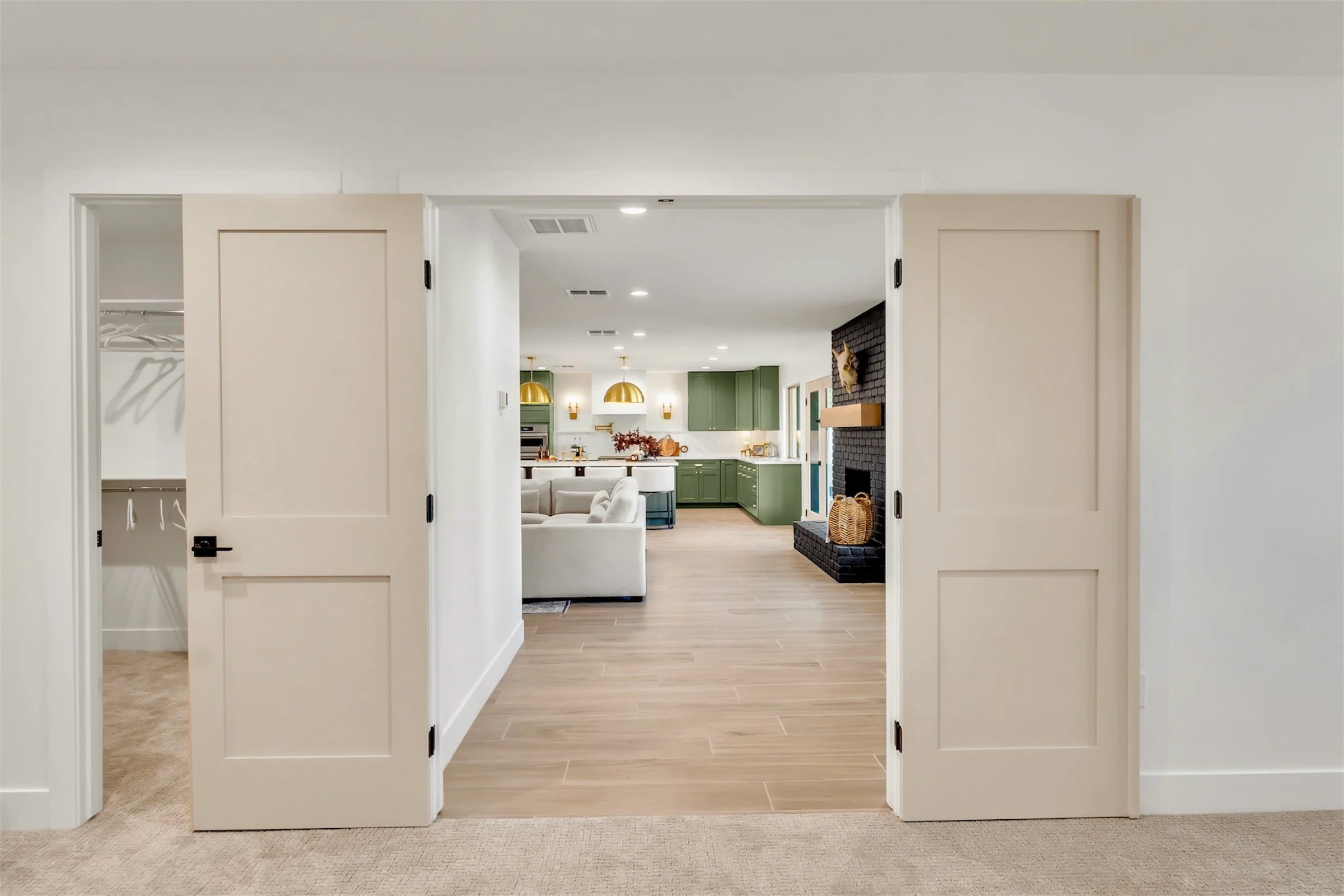 Interior view from bedroom in Phoenix, AZ showing open concept kitchen with green cabinetry and modern black fireplace.