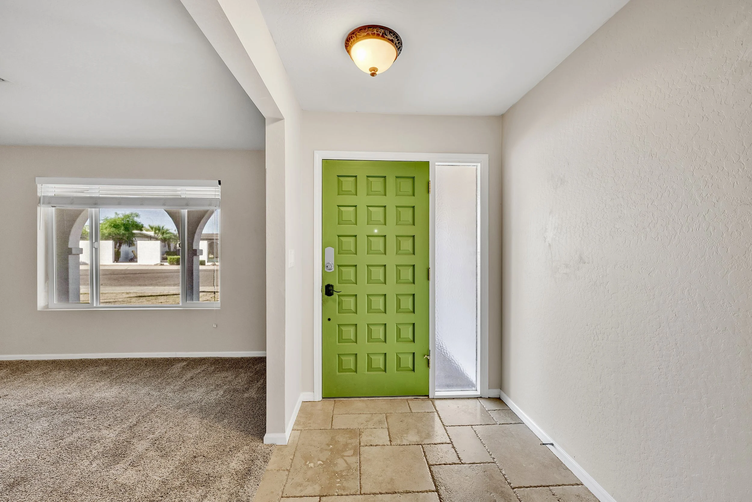 This bright entryway with a distinctive green door is captured in a real estate photography style in Tempe, AZ, showcasing the clean and inviting atmosphere of the home.