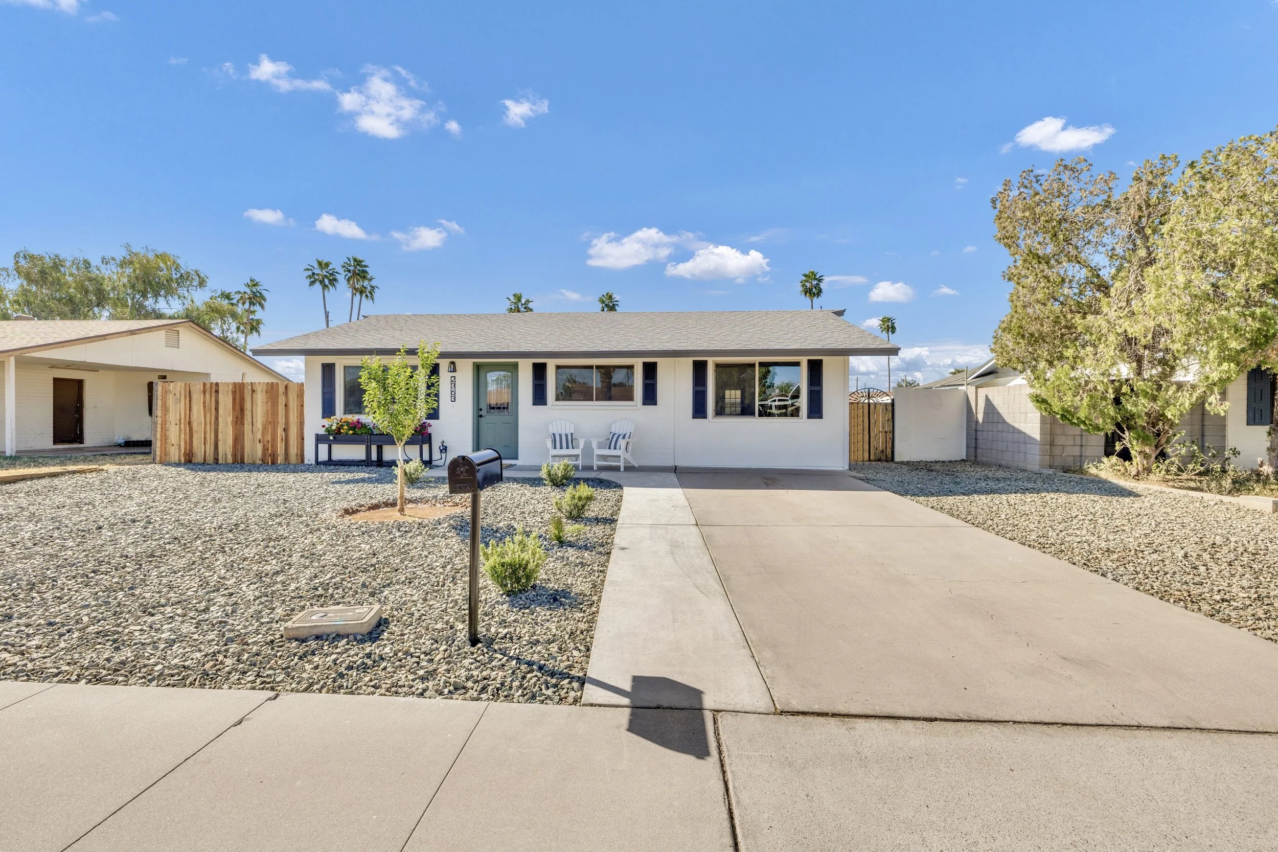 This single-story home in Mesa, AZ features a spacious front yard and driveway, captured with clear skies in this real estate photography.