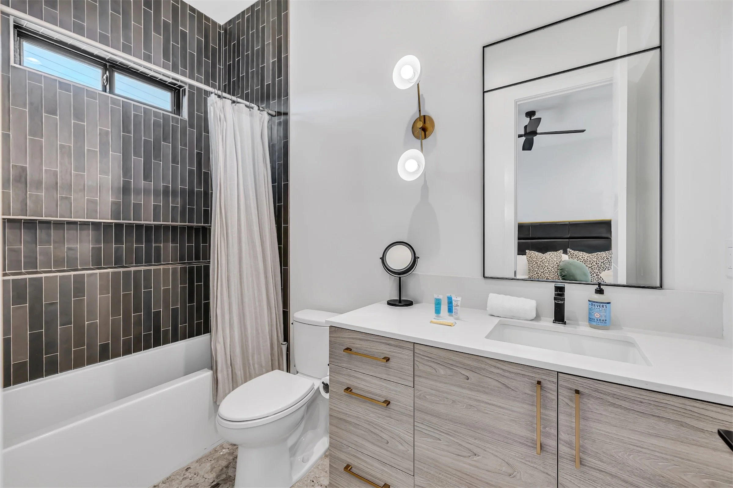 Bathroom with vertical tile tub-shower surround, modern wall lighting, and wood-grain vanity in Scottsdale, Arizona.