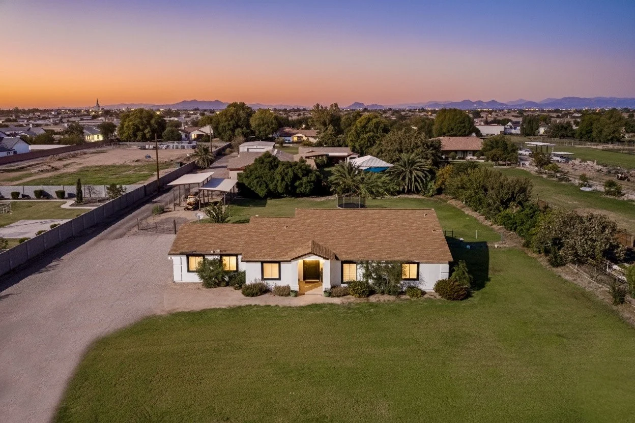 Aerial twilight real estate photography showcasing a single-story home with a spacious green lawn in Phoenix, AZ, capturing the scenic landscape and sunset hues perfectly.