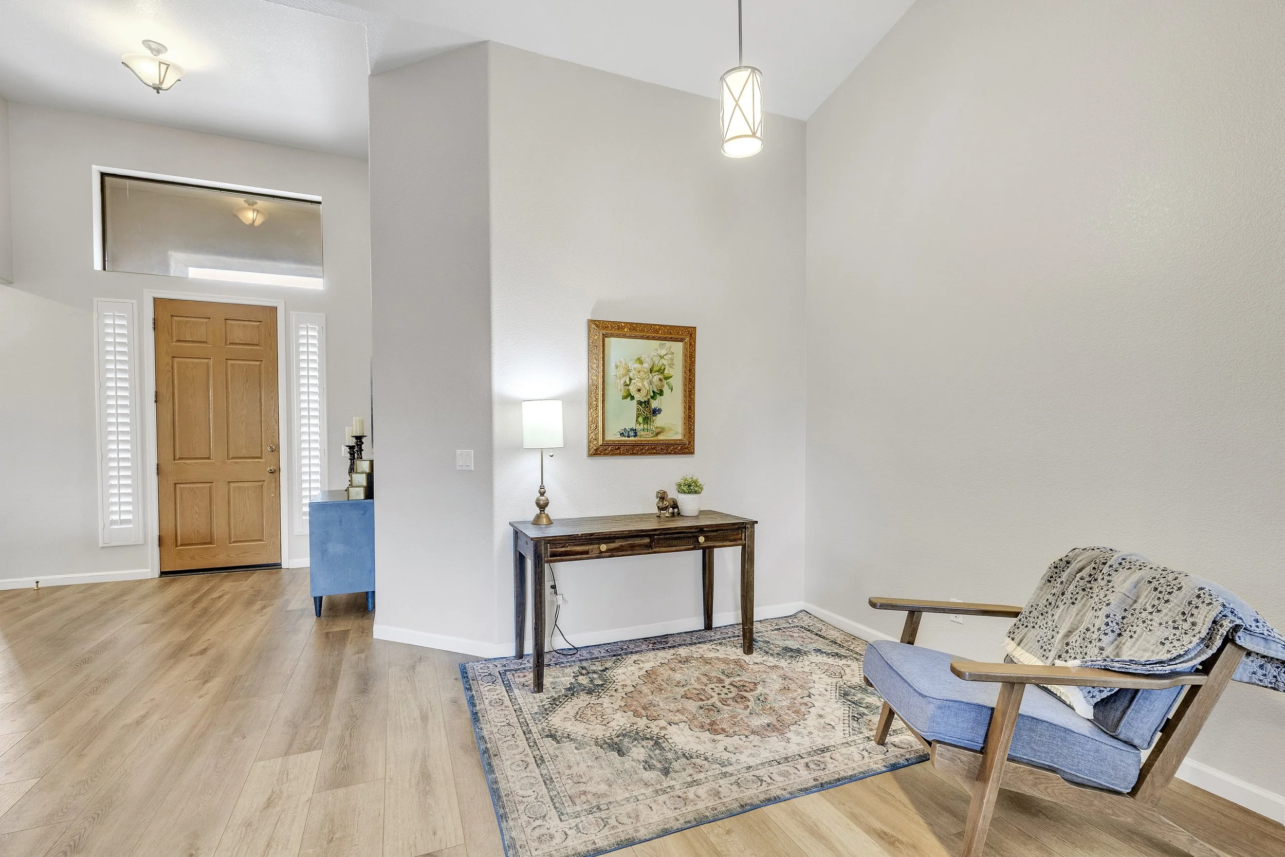 This image showcases the bright interior entryway and living room area in Goodyear, AZ, captured with professional real estate photography, highlighting the stylish decor and wood flooring.