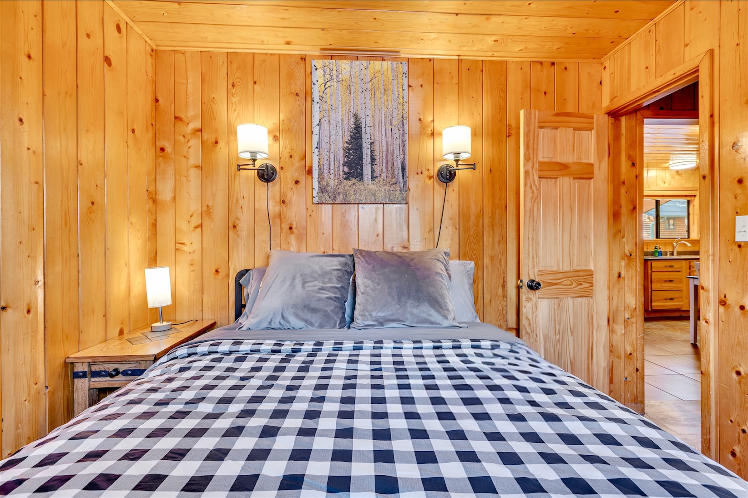 Cozy wood-paneled bedroom with a comfortable bed and soft lighting showcases this charming home in Greer, AZ, highlighted through professional real estate photography.
