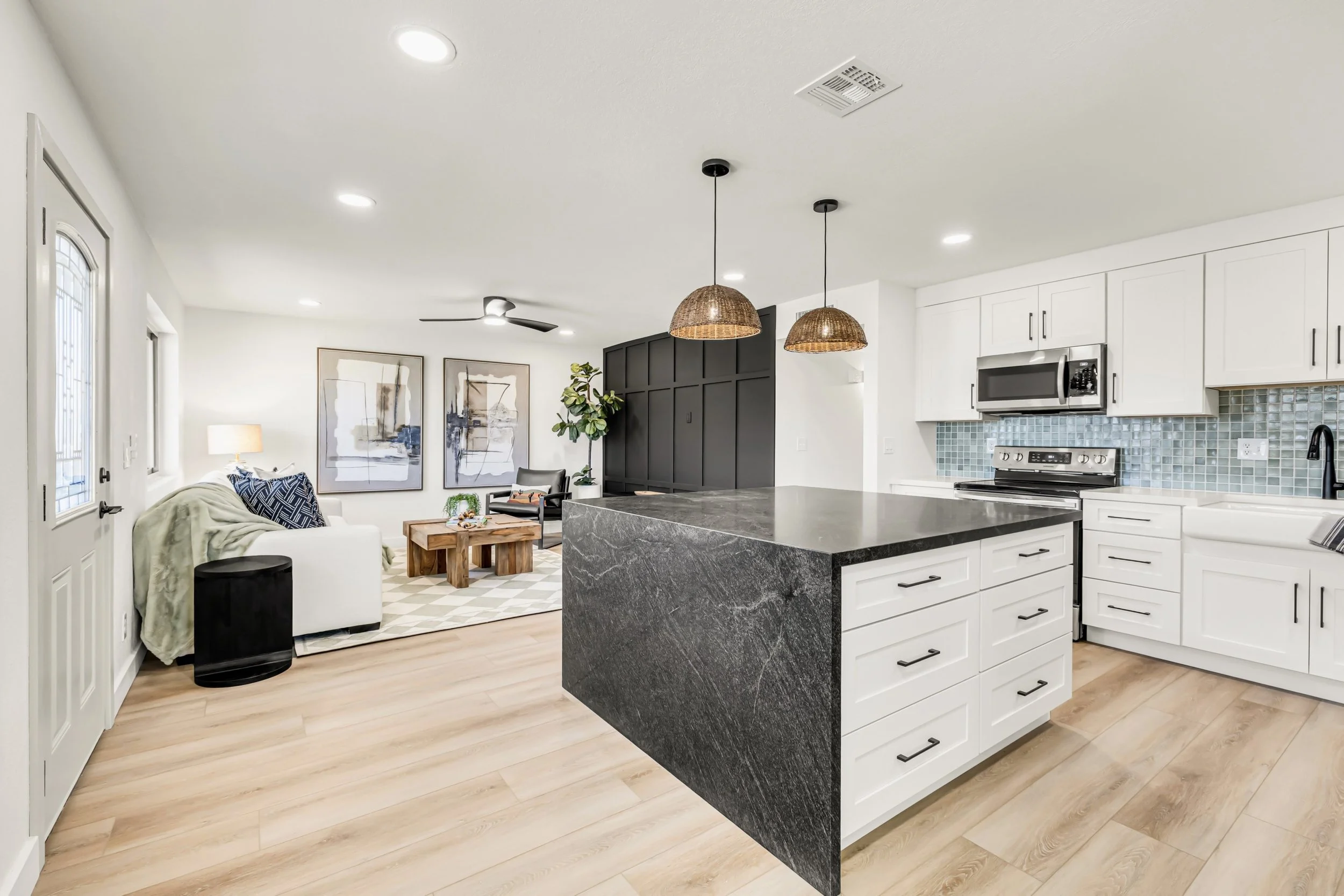 This bright, modern kitchen with a large island opens to a cozy living room, perfectly captured in real estate photography in Mesa, AZ.