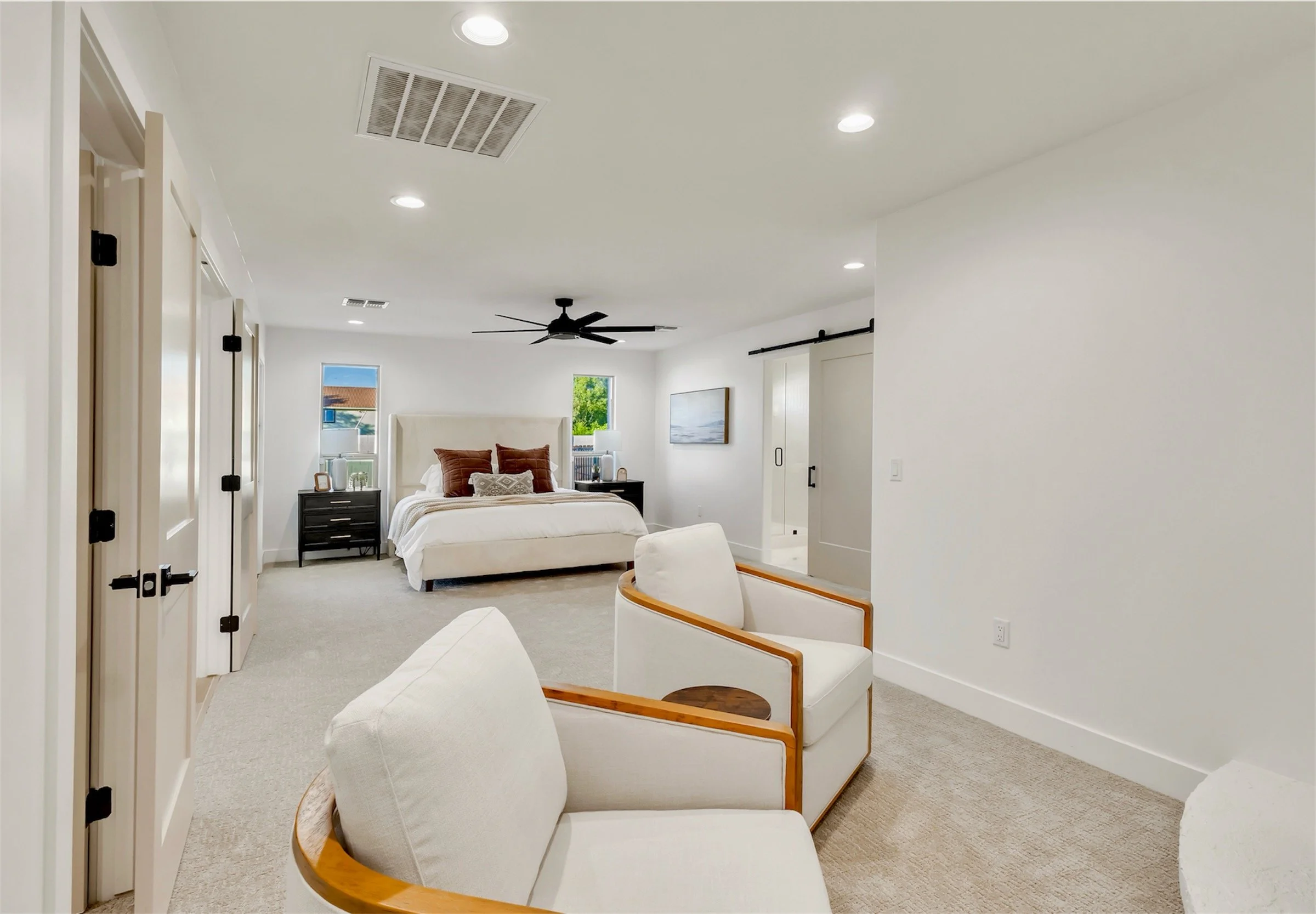 Spacious primary bedroom in Phoenix, AZ with a modern sitting area, barn door entry to ensuite, and soft neutral palette.