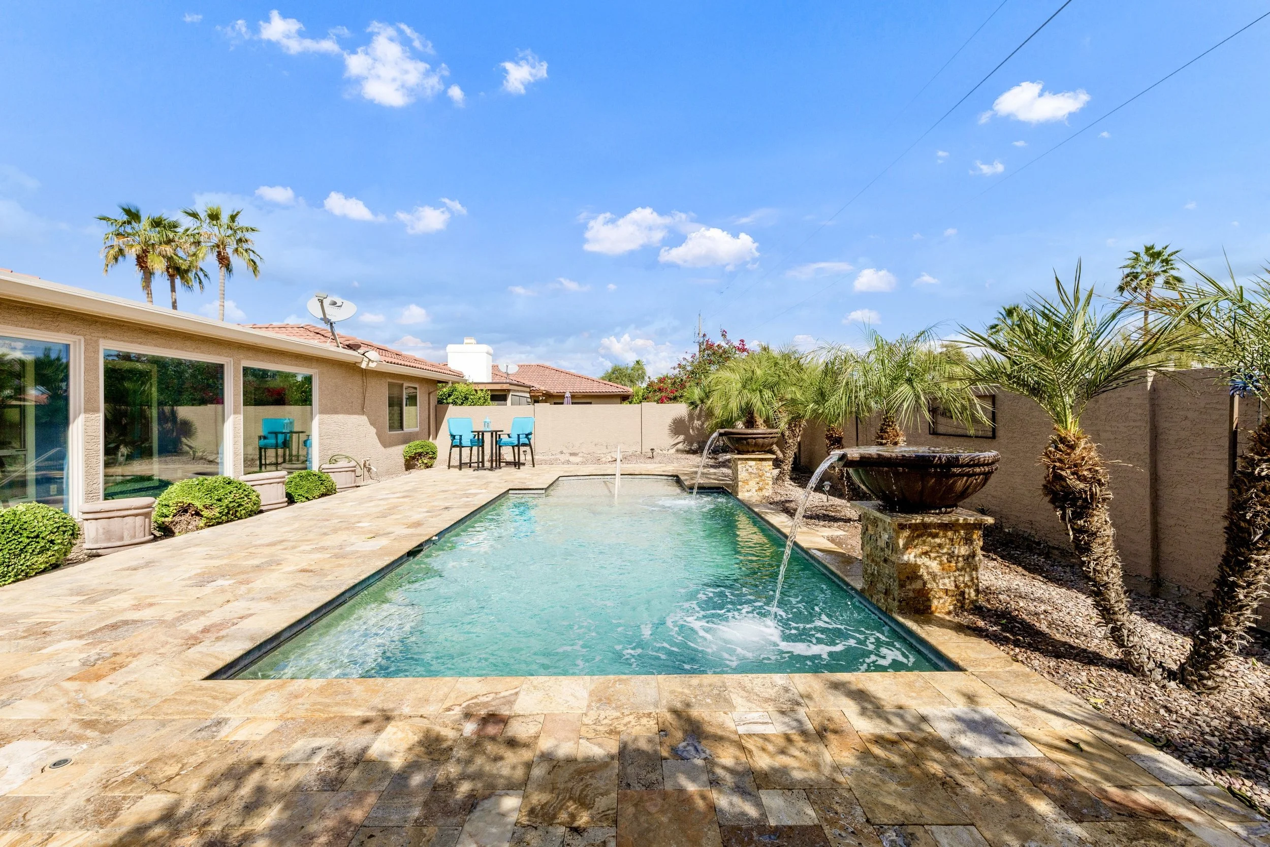 Beautiful backyard pool area with water features and palm trees captured in real estate photography in Sun Lakes, AZ.