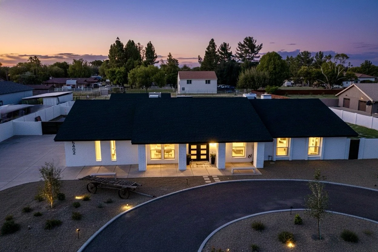 Stunning twilight real estate photography showcasing a beautifully lit modern home exterior in Phoenix, AZ, with a spacious driveway and well-maintained landscaping.