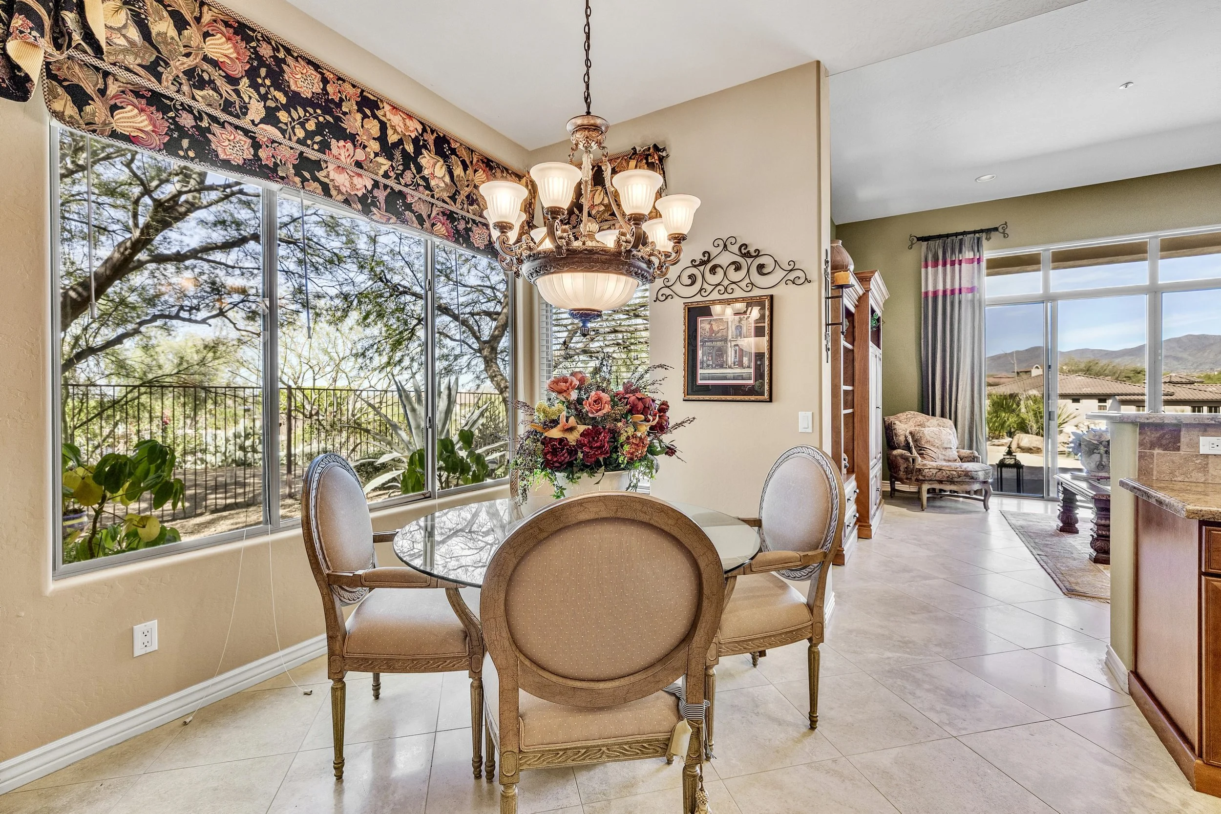 This Scottsdale, AZ dining area features large windows with scenic views, elegant chandelier lighting, and classic furniture, exemplifying exceptional real estate photography.