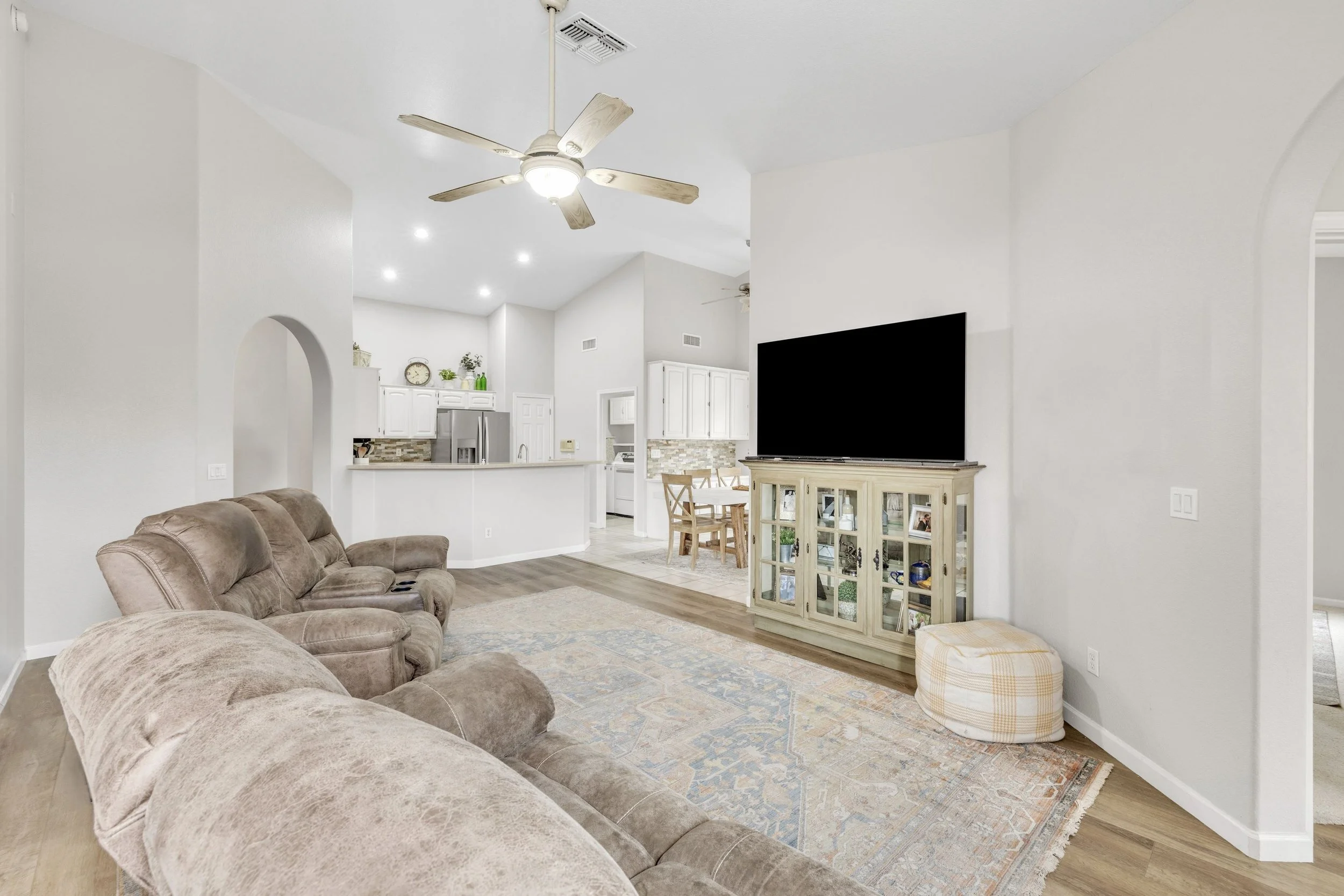 Bright living room with vaulted ceilings and open kitchen area in a Goodyear, AZ home captured with real estate photography.