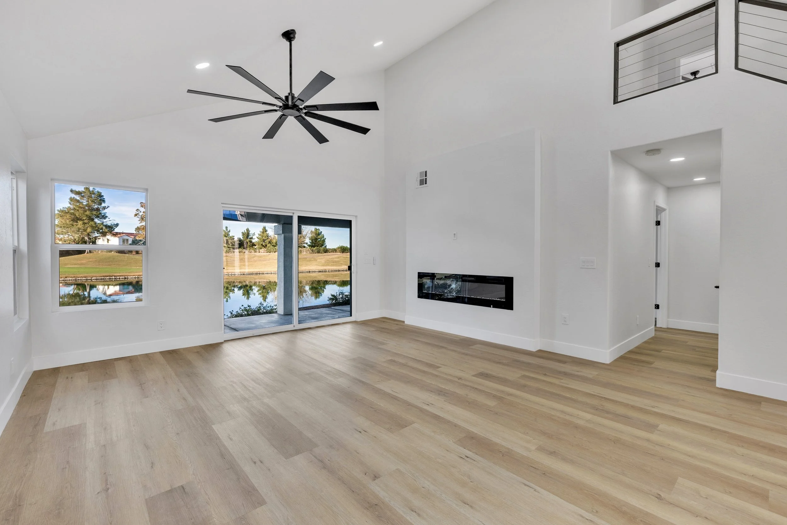 This bright living room in Chandler, AZ features modern real estate photography showcasing high ceilings, a sleek fireplace, and large windows with serene water views.