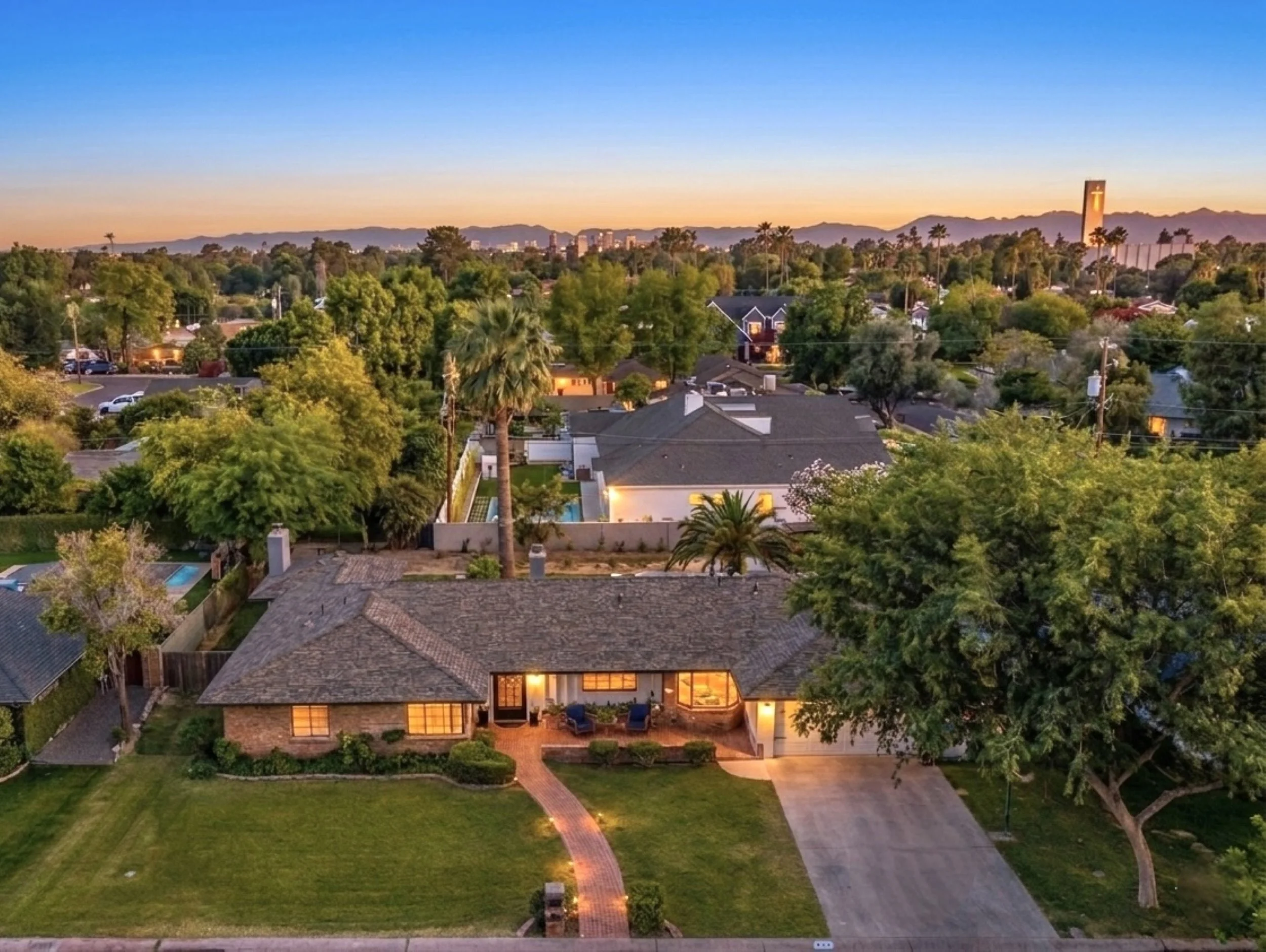 Stunning aerial real estate photography of suburban homes at sunset in Phoenix, AZ, showcasing lush greenery and a tranquil neighborhood ambiance.