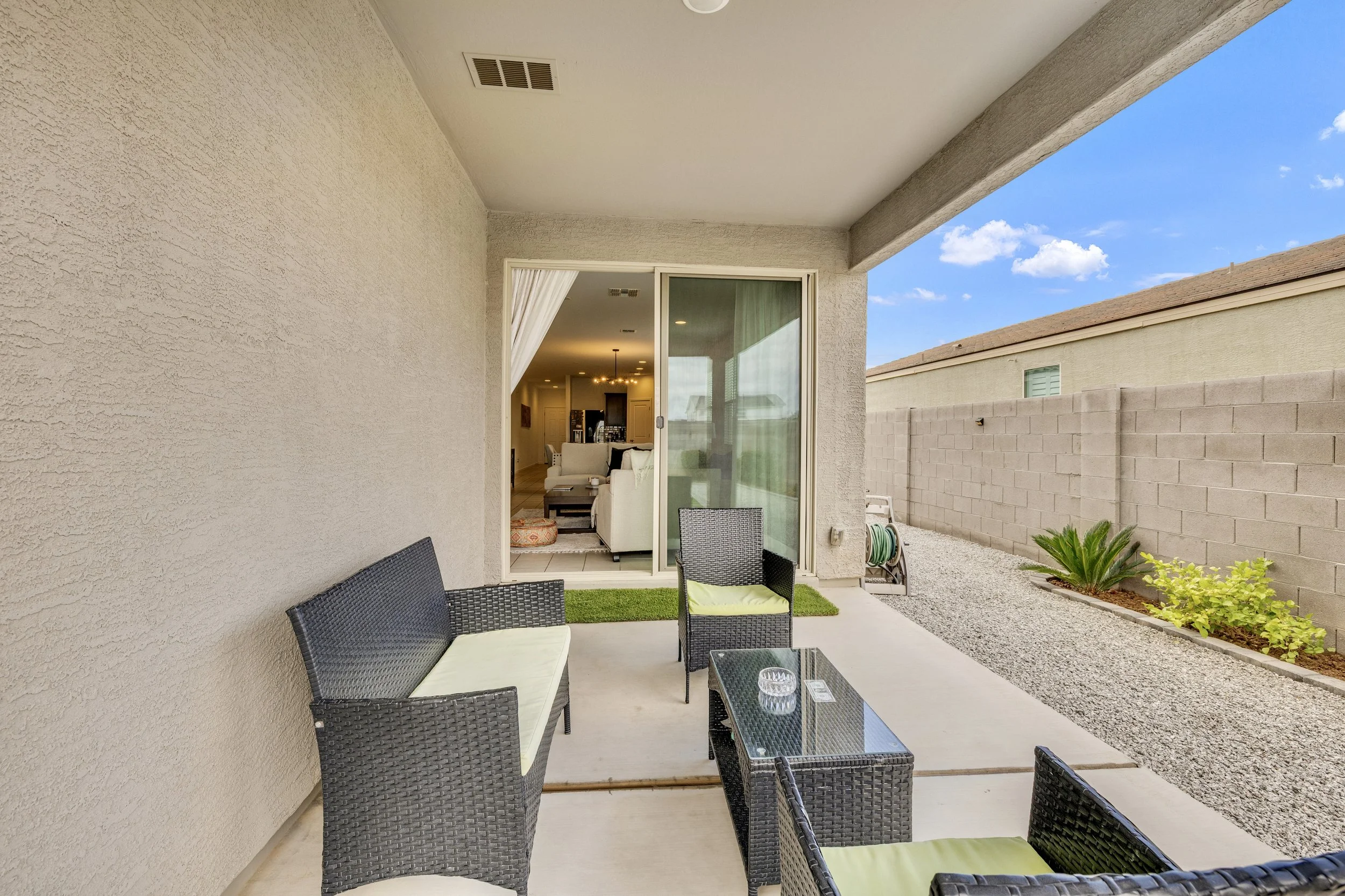 This covered patio with outdoor seating offers a cozy space in San Tan Valley, AZ, perfect for relaxing and entertaining, showcased through expert real estate photography.