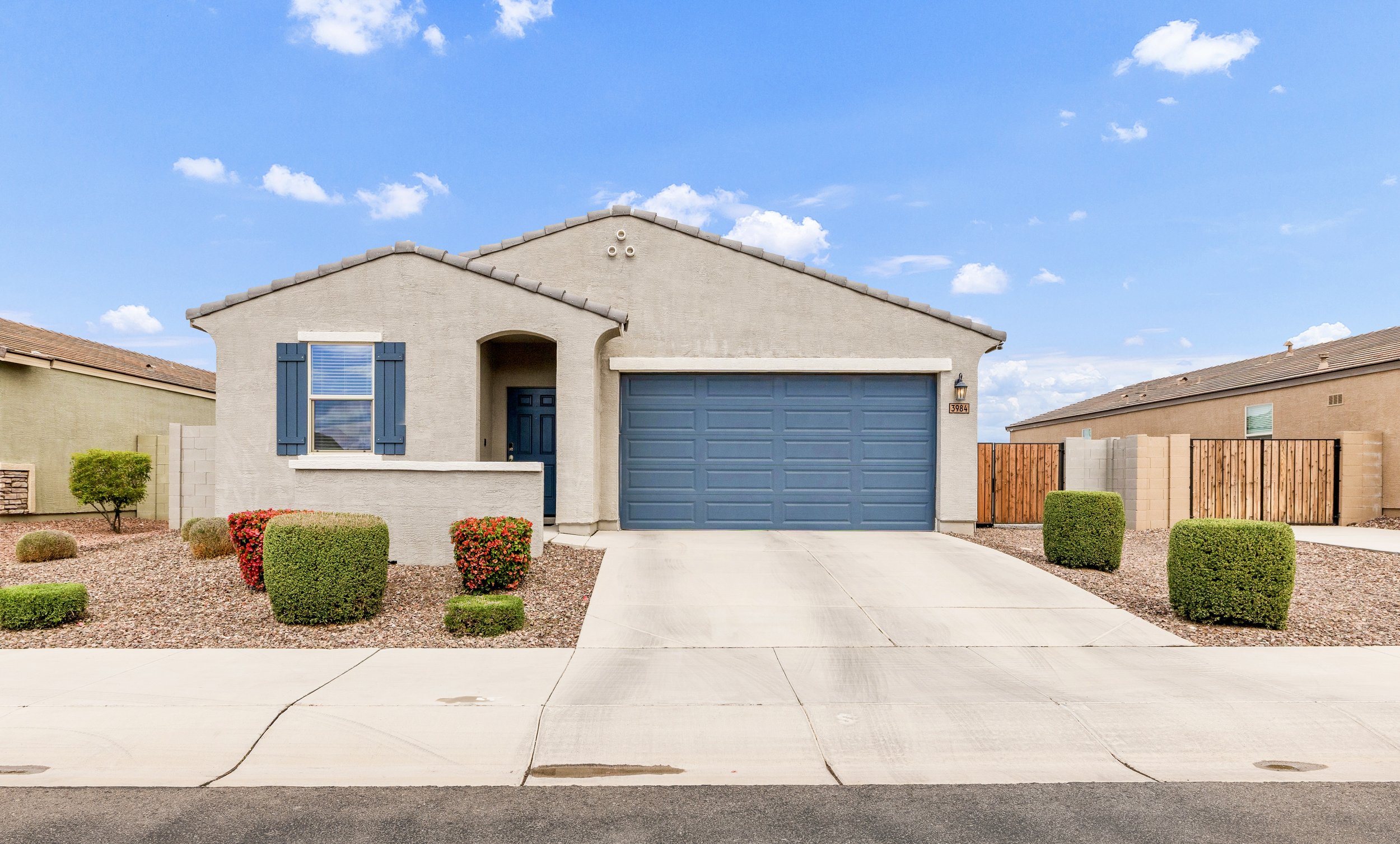 A charming stucco home with a blue garage door and manicured desert landscaping is showcased in this real estate photography in San Tan Valley, AZ.