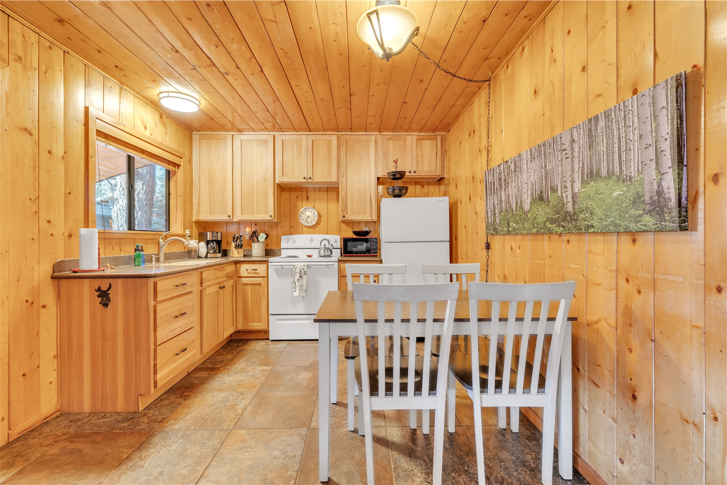 This cozy wood-paneled kitchen and dining area in Greer, AZ features modern appliances and real estate photography highlights the warm, inviting space perfect for comfortable living.