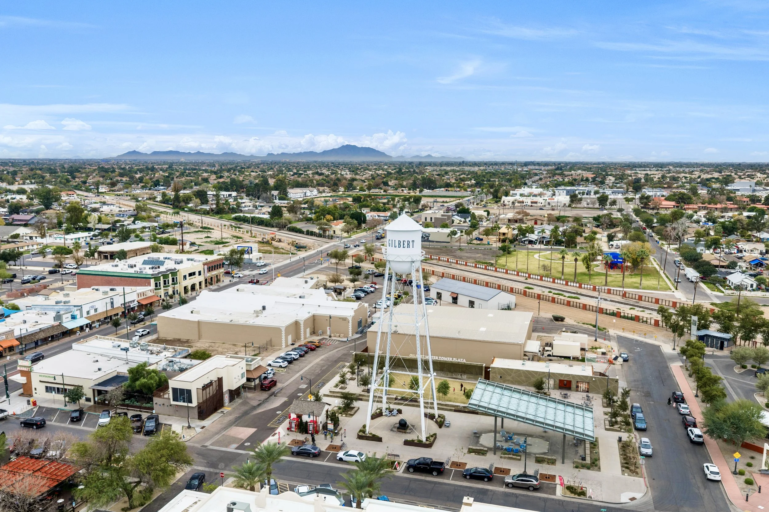 High-altitude drone photo overlooking downtown Gilbert Arizona featuring the iconic Gilbert water tower and surrounding streets.