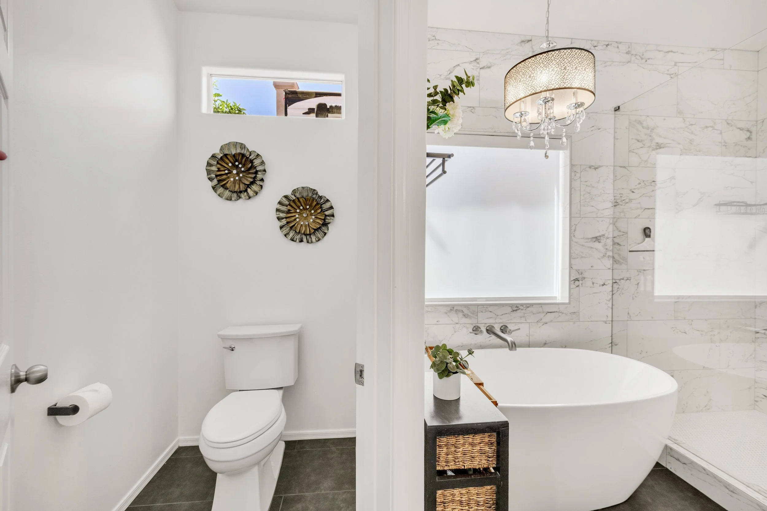 This modern bathroom in Gilbert, AZ features a clean toilet area, luxurious freestanding bathtub, and glass-enclosed shower, captured with expert real estate photography for optimal presentation.