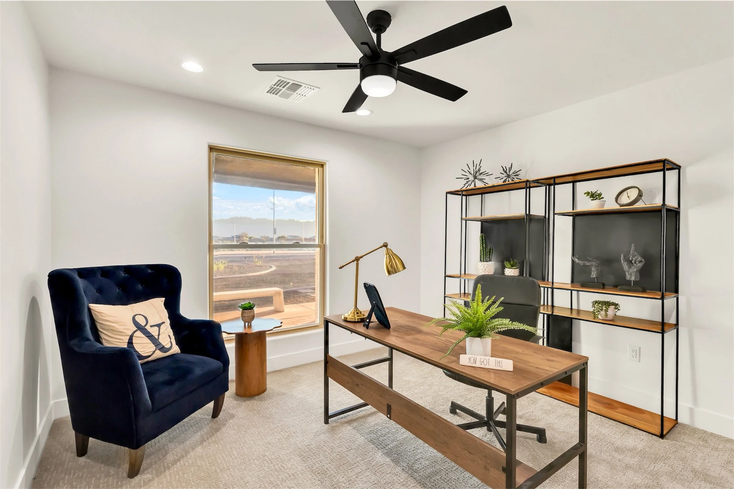 Modern home office with large window, black ceiling fan, and wood desk in a bright Phoenix, AZ house.
