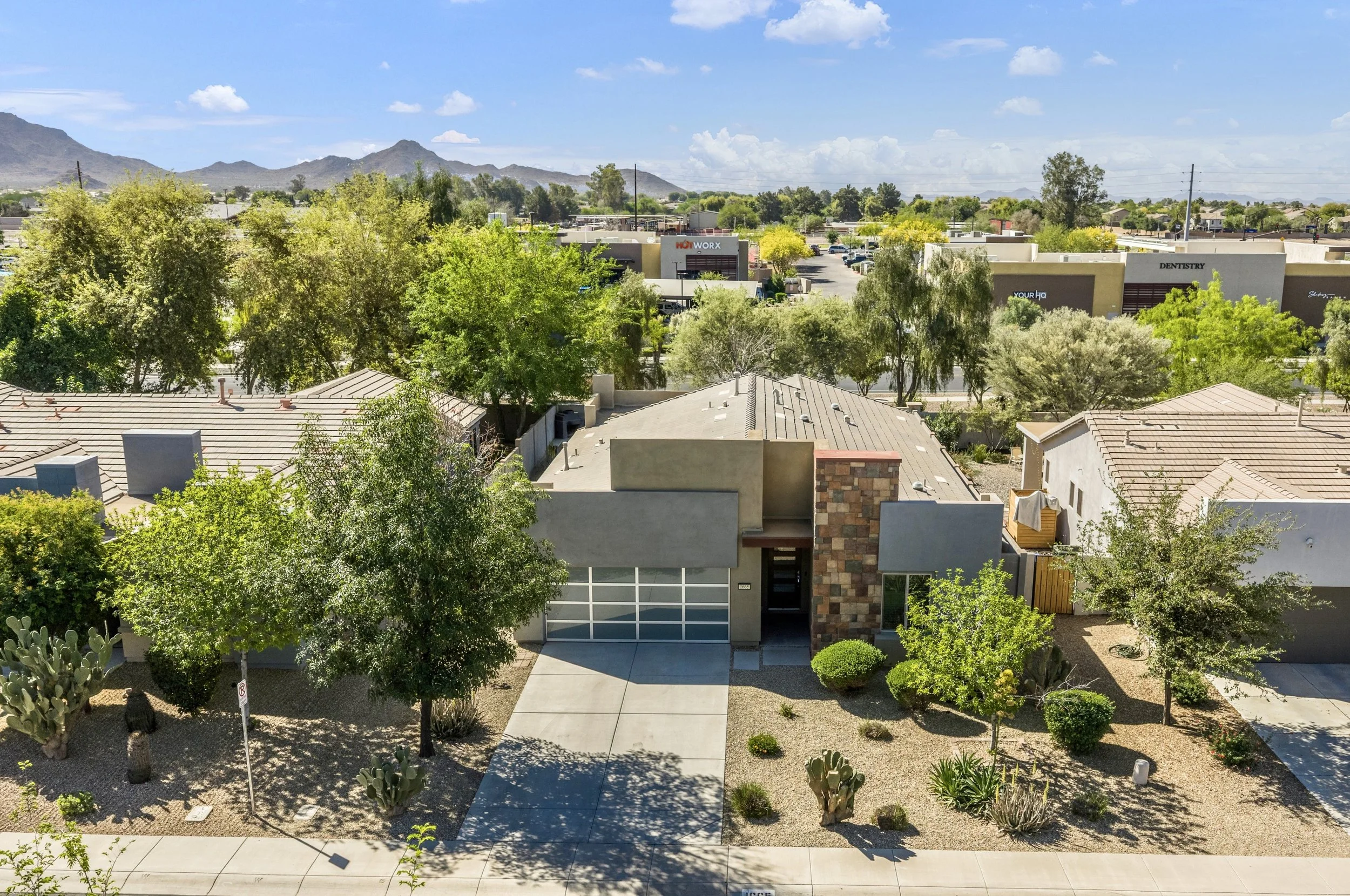 Aerial exterior view of a modern home front in Gilbert, AZ, showcasing landscaping and surrounding neighborhood in this real estate photography image.