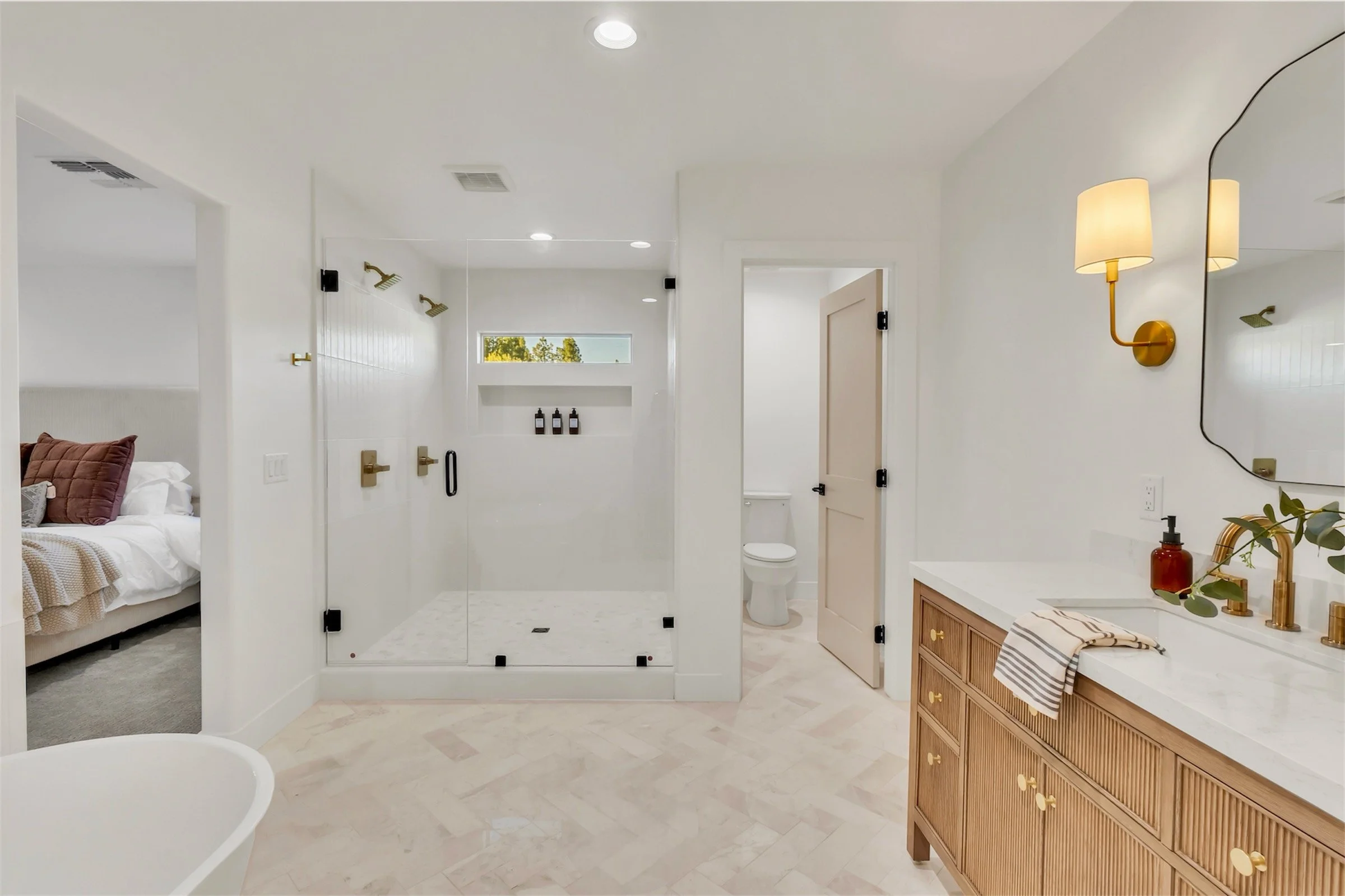 Luxurious walk-in shower with gold fixtures, glass enclosure, and herringbone tile flooring in a modern Phoenix, AZ bathroom.