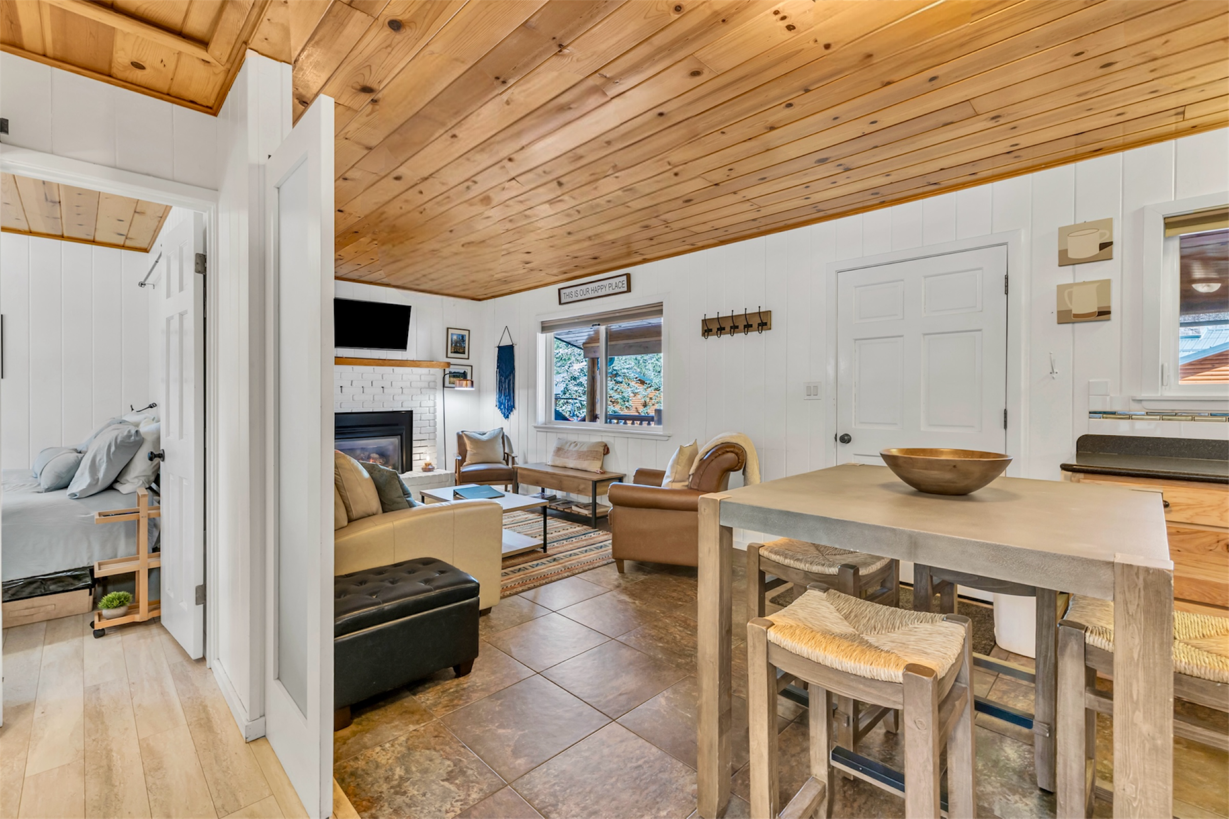 This cozy living room and dining area feature a wooden ceiling and modern fireplace in a Greer, AZ home, captured with expert real estate photography to showcase warmth and comfort.
