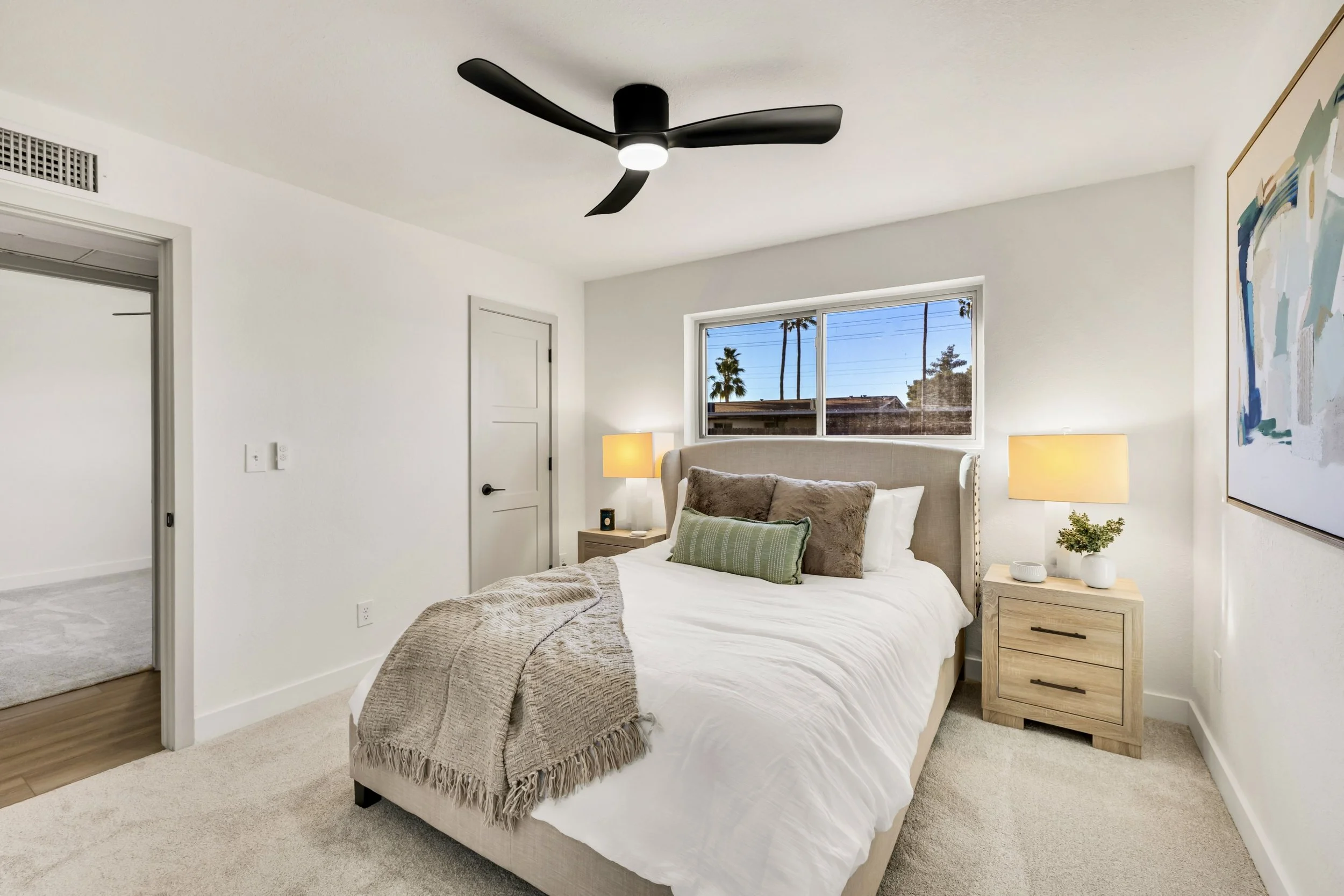 This modern bedroom in Mesa, AZ features a stylish ceiling fan, cozy bedding, and soft lighting, captured through expert real estate photography to highlight comfort and design.