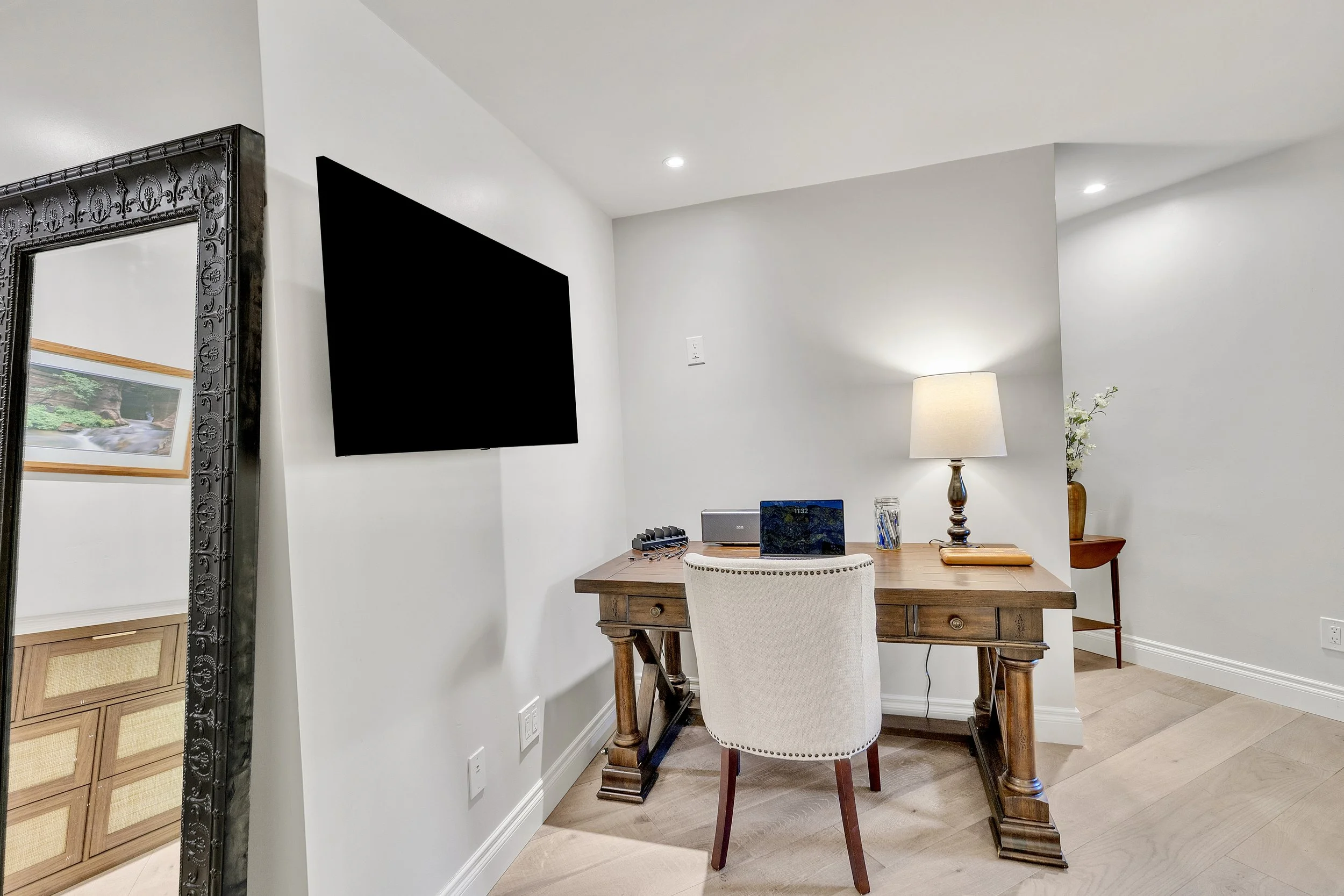 This cozy home office in Paradise Valley, AZ features a wooden desk, modern lamp, and wall-mounted TV, captured with professional real estate photography to highlight the inviting workspace.