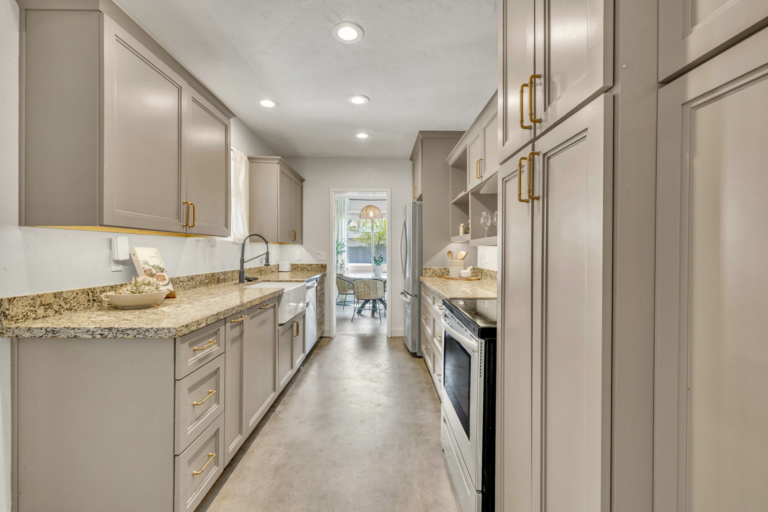 This modern galley kitchen features sleek cabinetry and granite countertops in a Phoenix, AZ home, showcased through professional real estate photography.