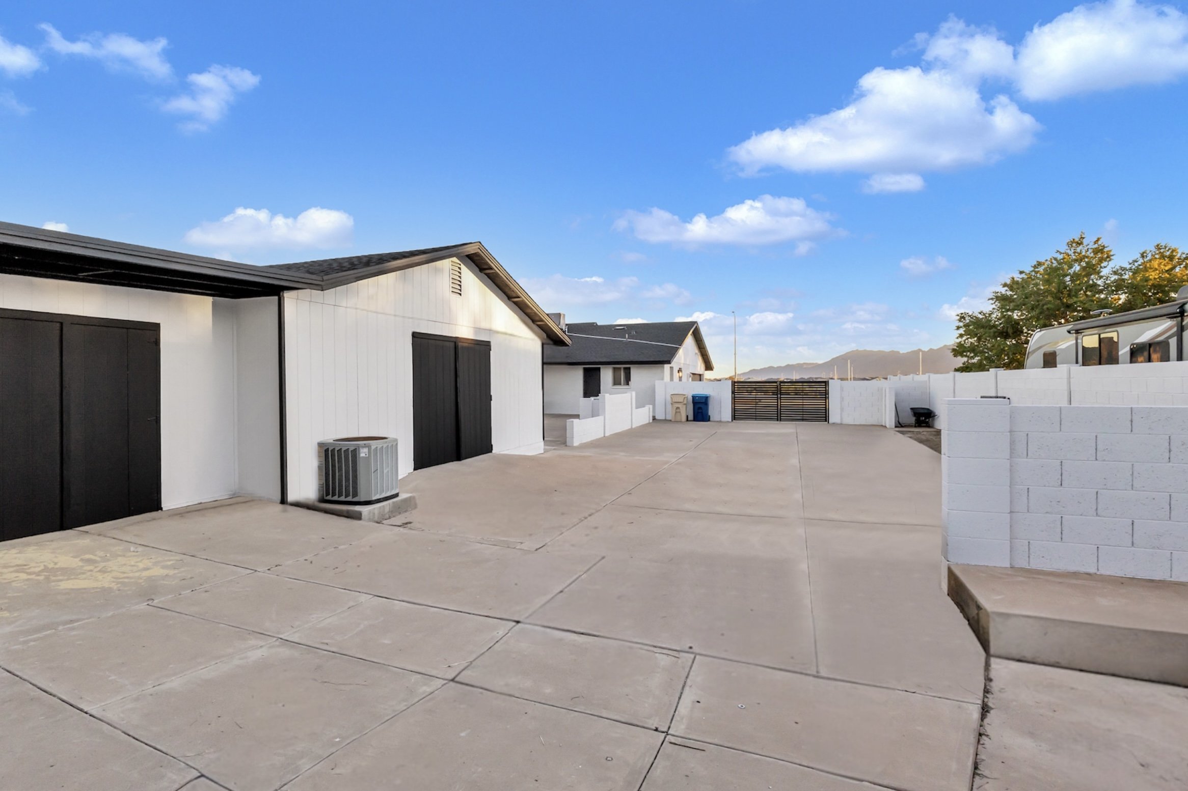 Spacious driveway and detached garage at a Phoenix, AZ property featuring mountain views, modern exterior paint, and RV parking area.