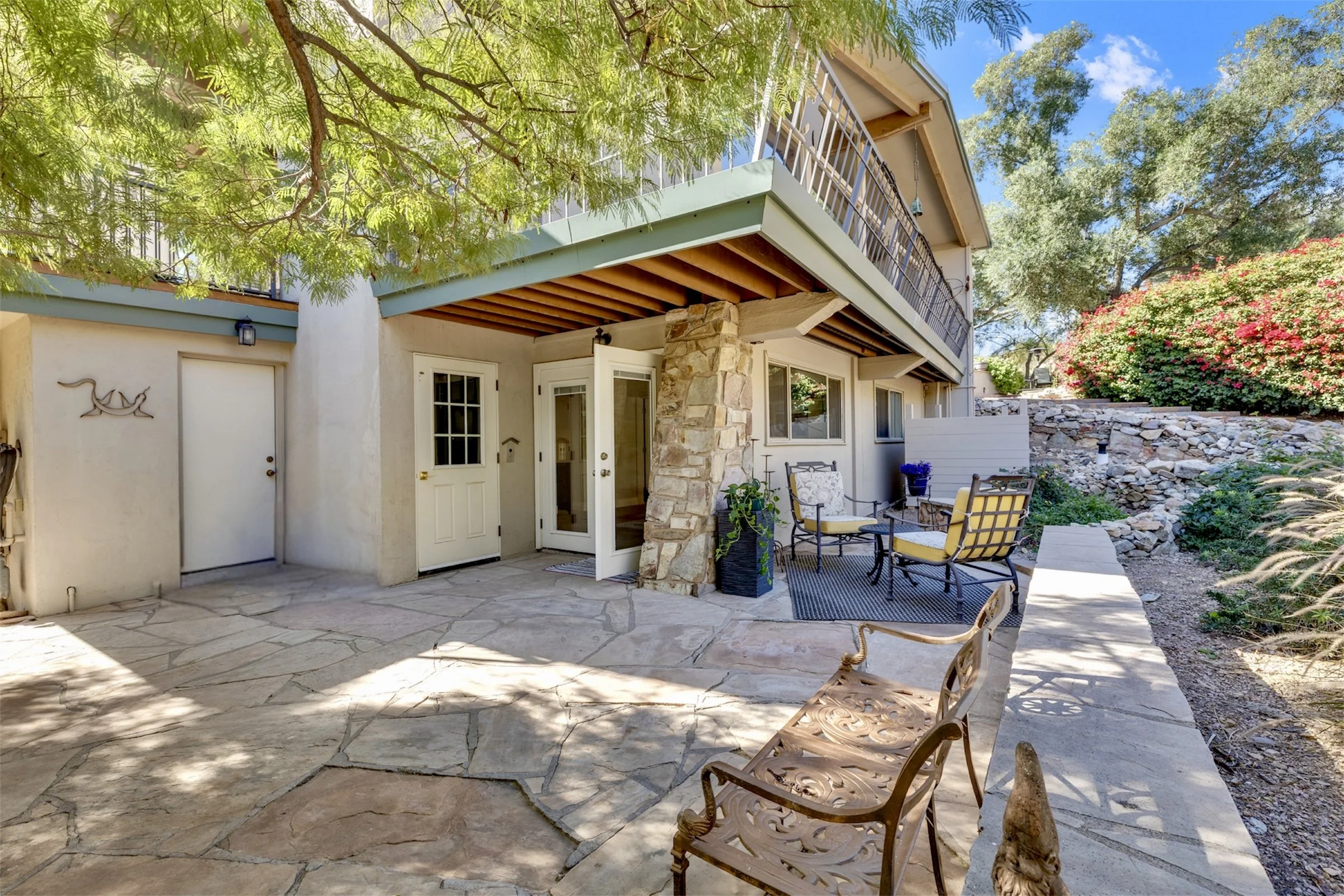 This exterior backyard patio in Paradise Valley, AZ features a stone floor and comfortable seating area, showcased with professional real estate photography for an inviting outdoor living space.