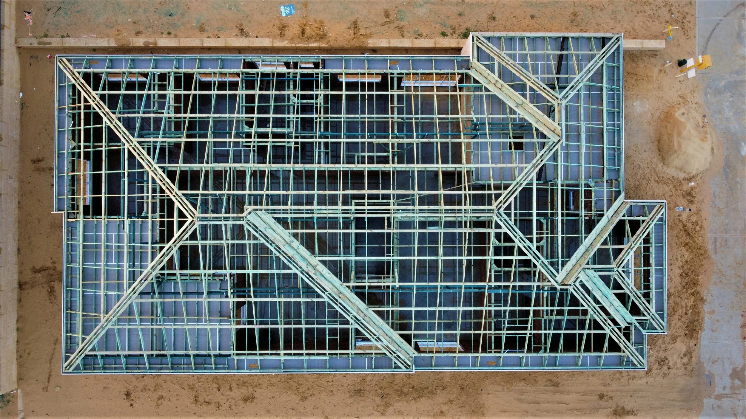 Top view of a building under construction with metal framework and wooden beams.