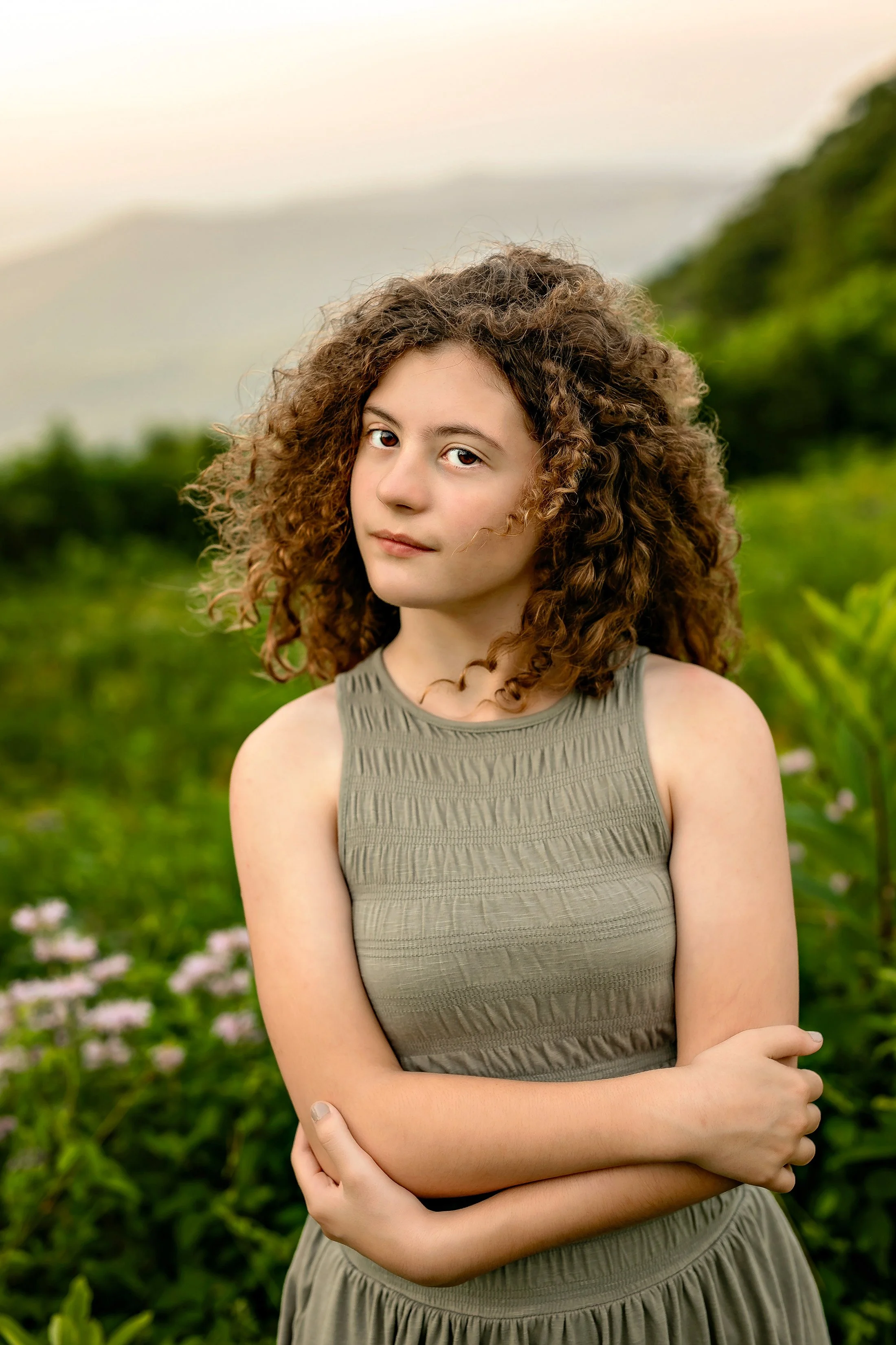 A young girl poses in a field of flowers with the Shenandoah mountains in the background during her session with Worthy of Love Photography a Shenandoah Valley photographer