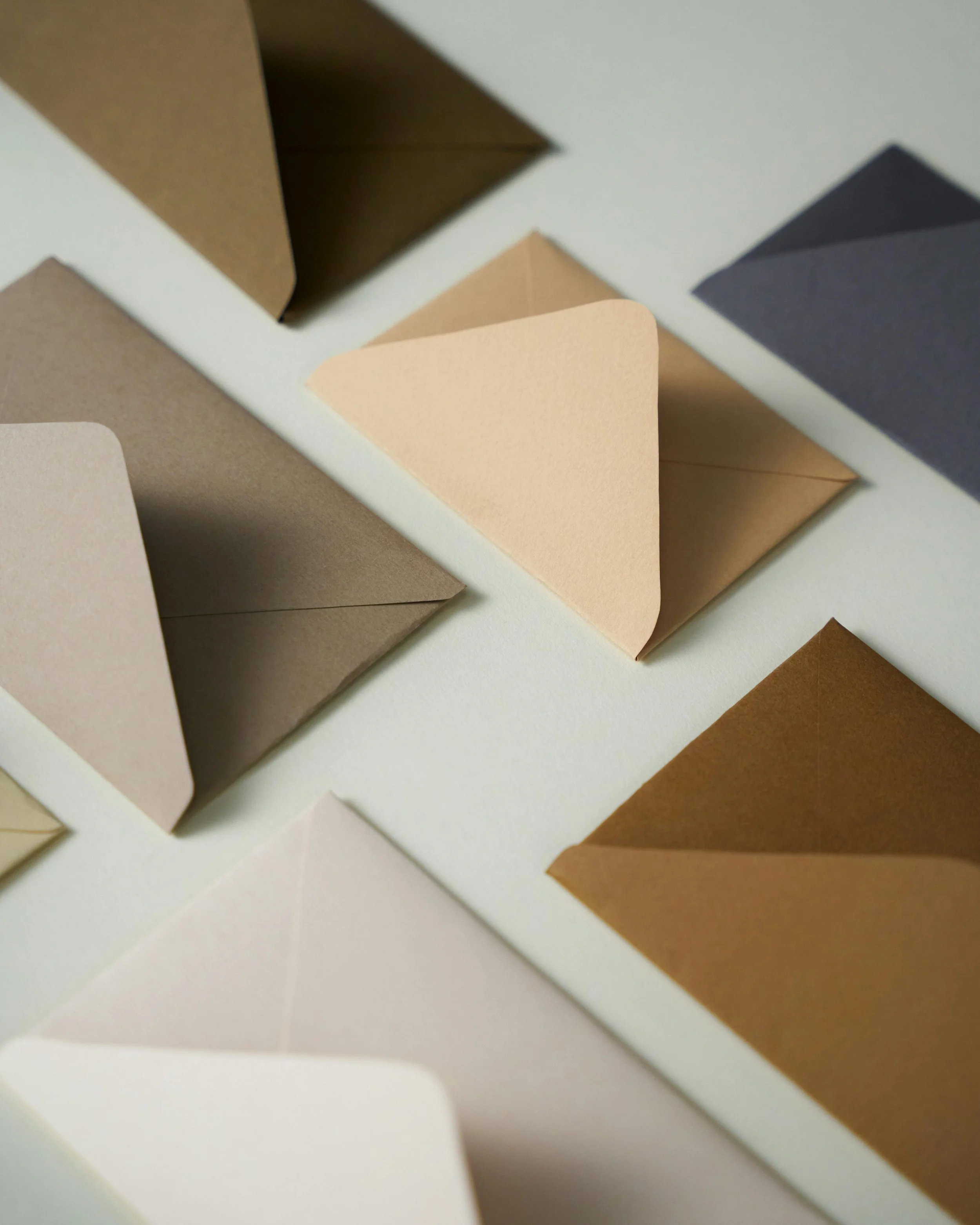 Assorted folded paper in various neutral colors arranged on a white surface.
