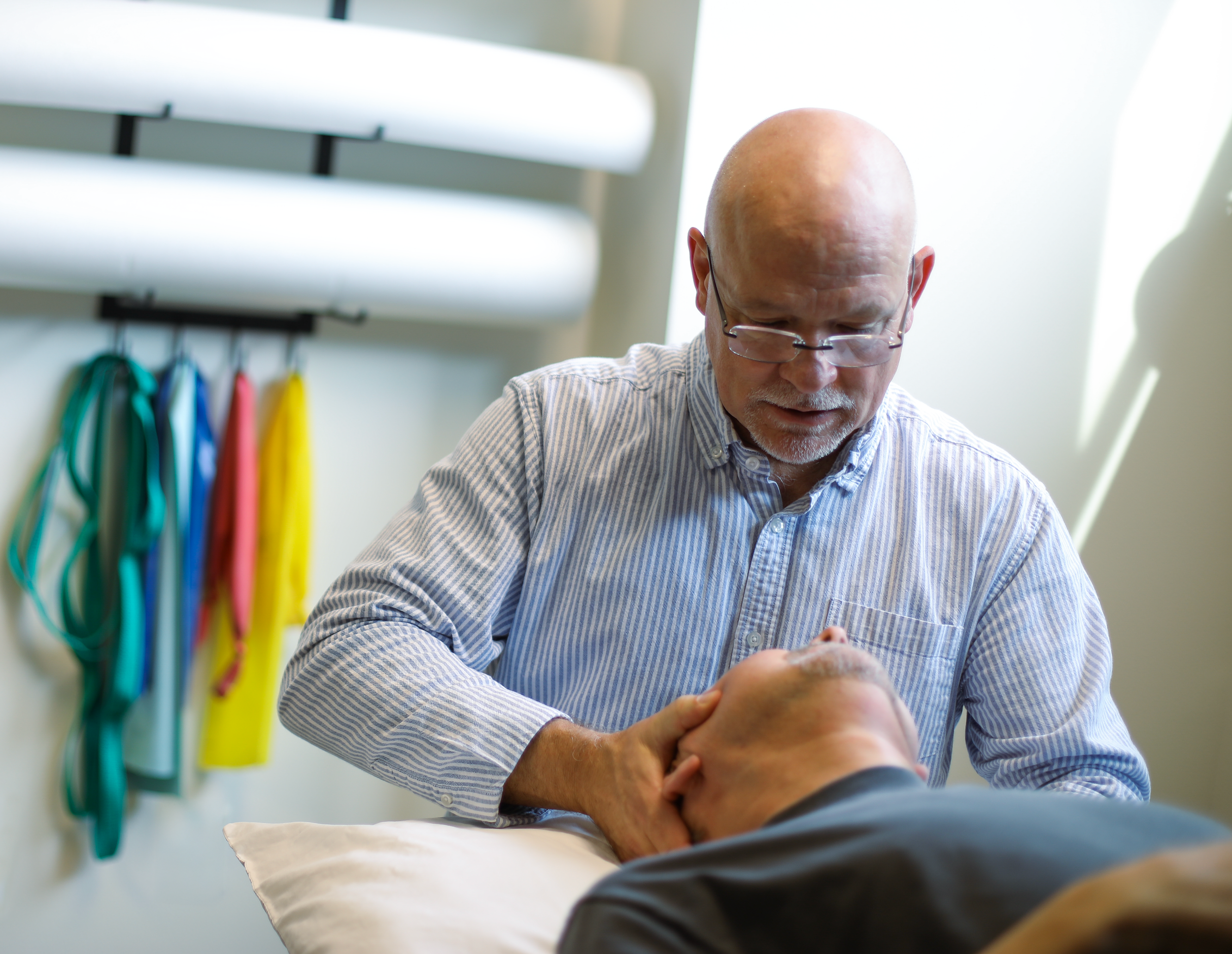 A healthcare professional performing a neck chiropractic adjustment on a patient lying on an examination table.