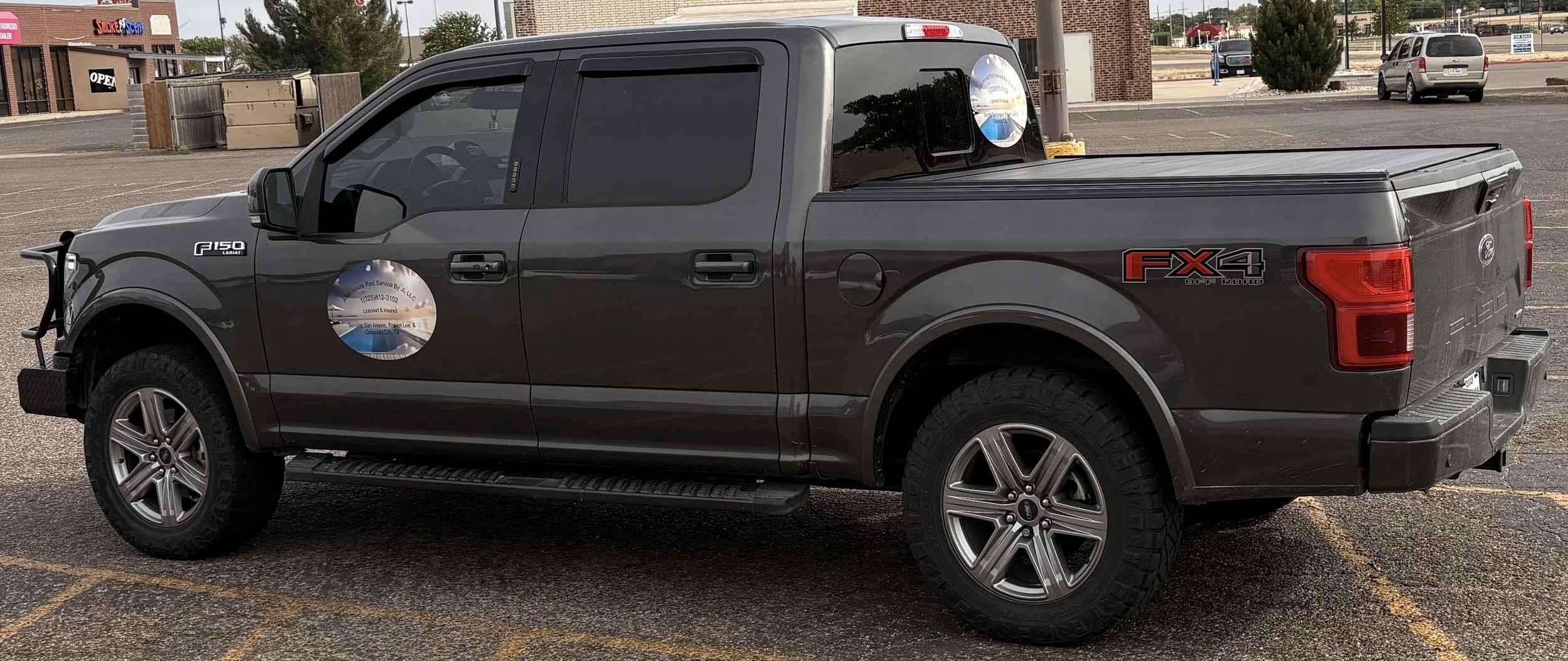 Gray Ford F-150 pickup truck parked in a lot, with the FX4 Off Road badge on the side and a circular decal on the door.
