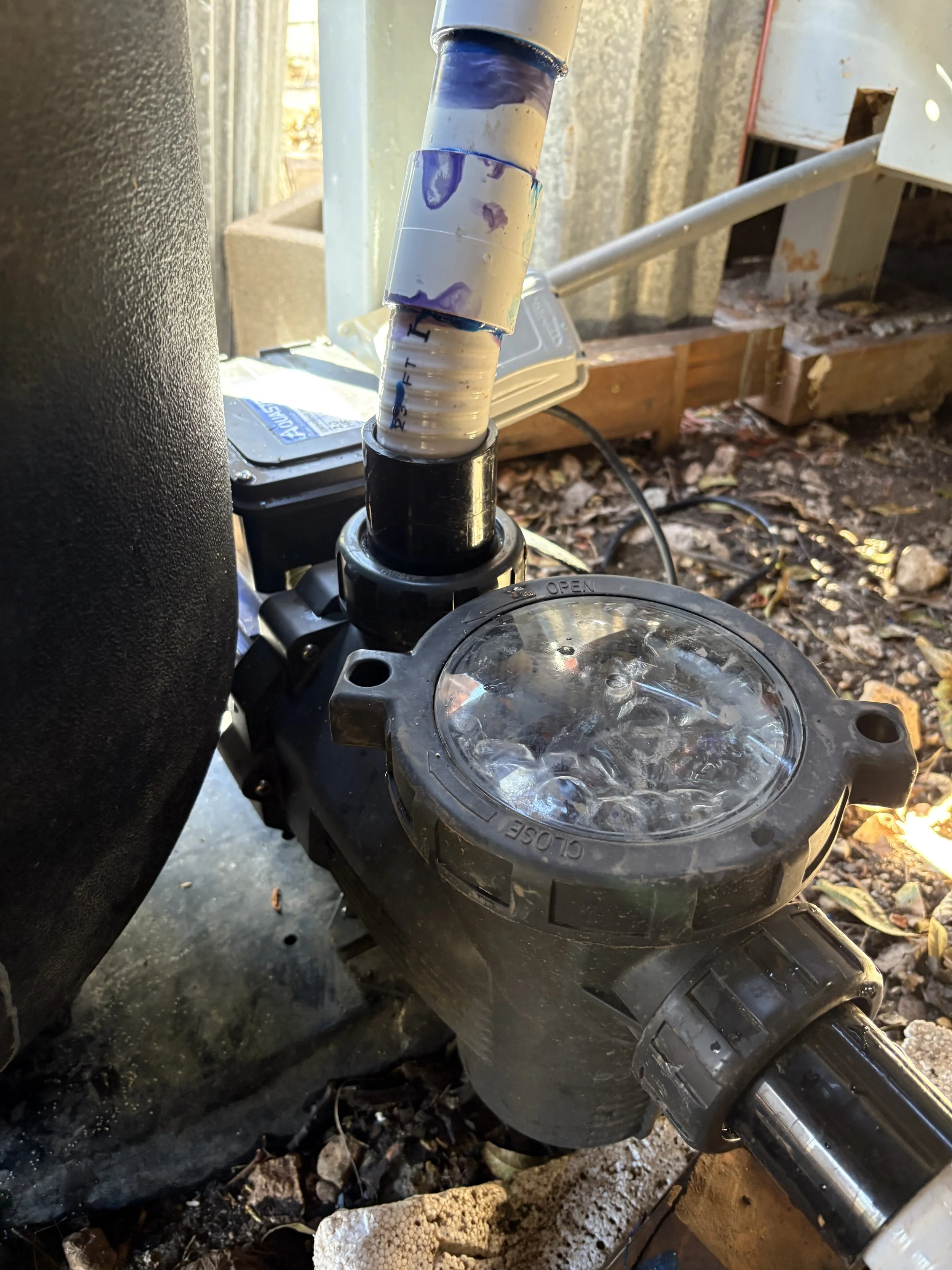 Close-up of a motorcycle handlebar with a motion blur of the front wheel and a tire, surrounded by outdoor debris and soil.