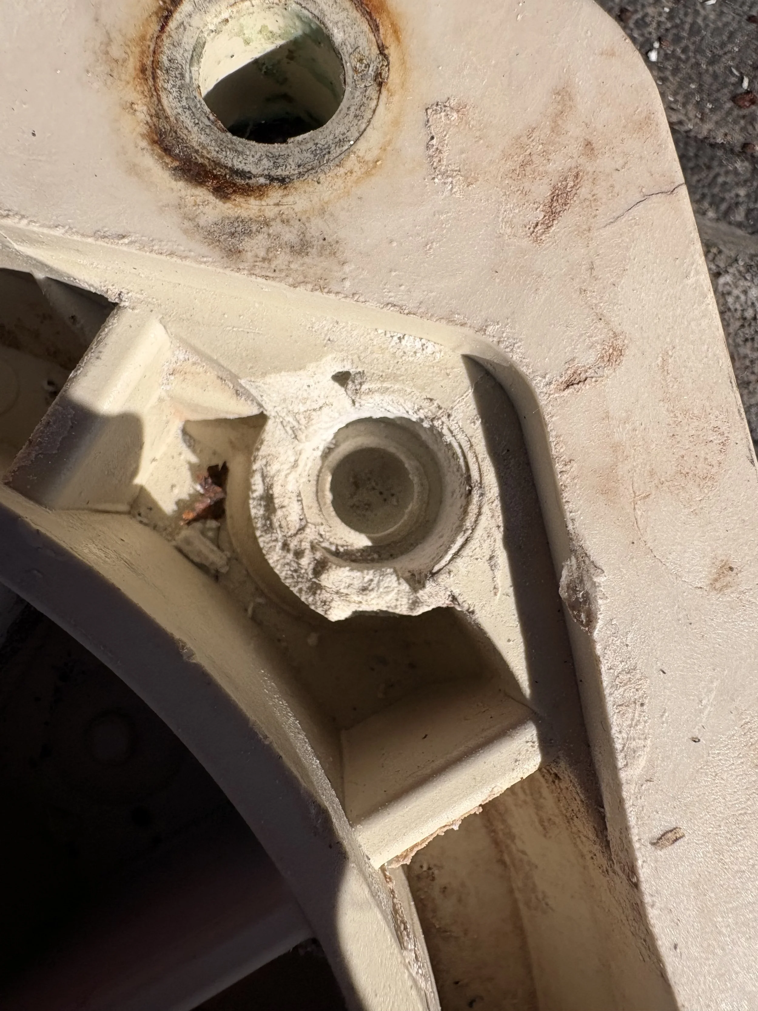 Close-up of a metal structure with visible rust and corrosion, featuring two circular openings and chipped paint.