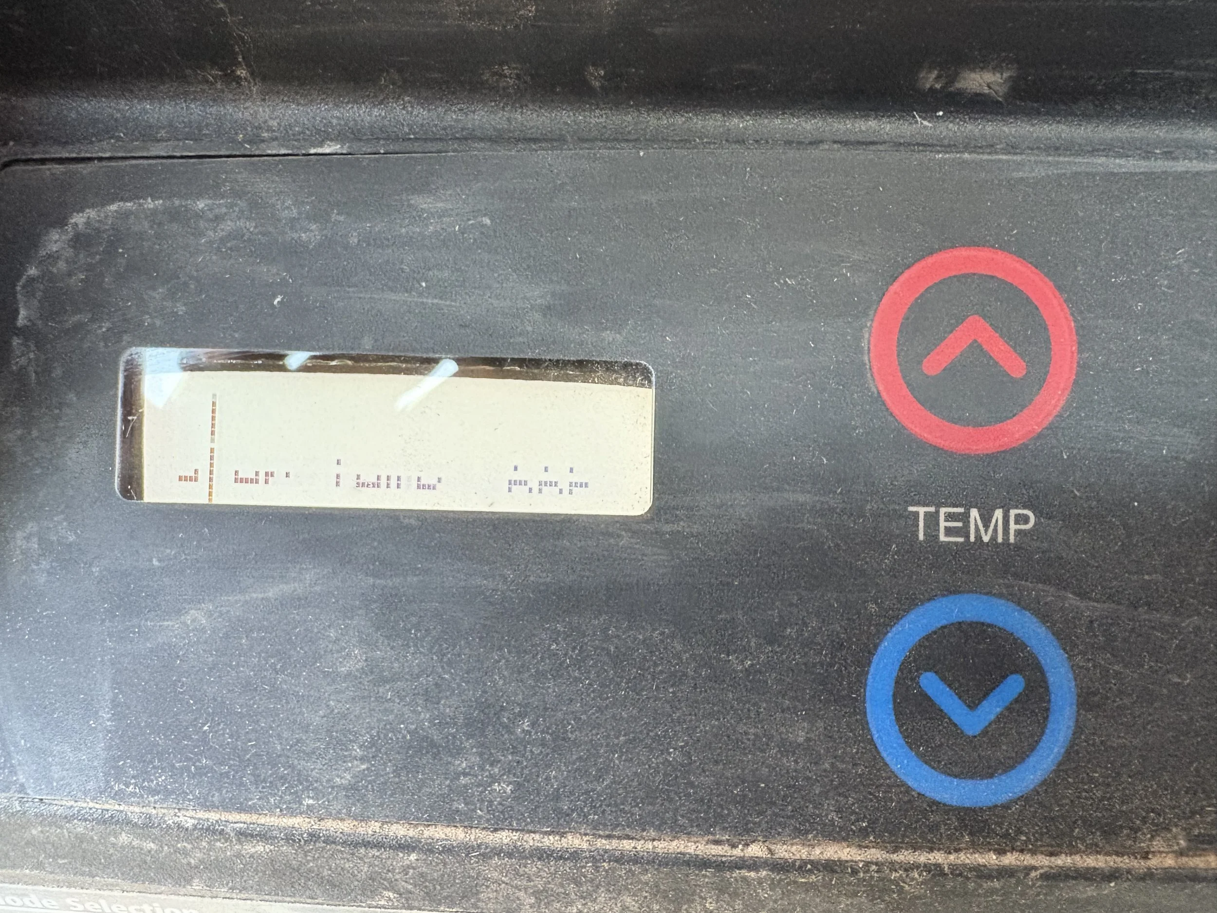 Close-up of a digital control panel with an upward arrow button and a temperature indicator.
