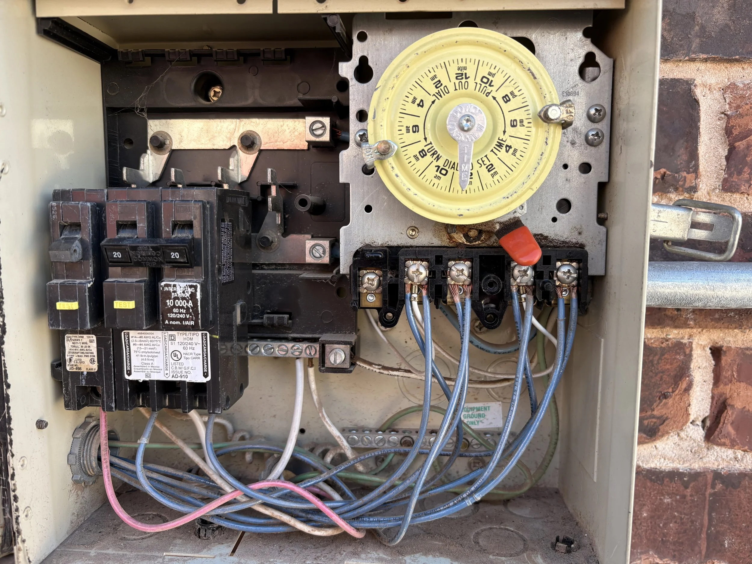 Inside an electrical box with various wires, circuit breakers, and a yellow dial timer.