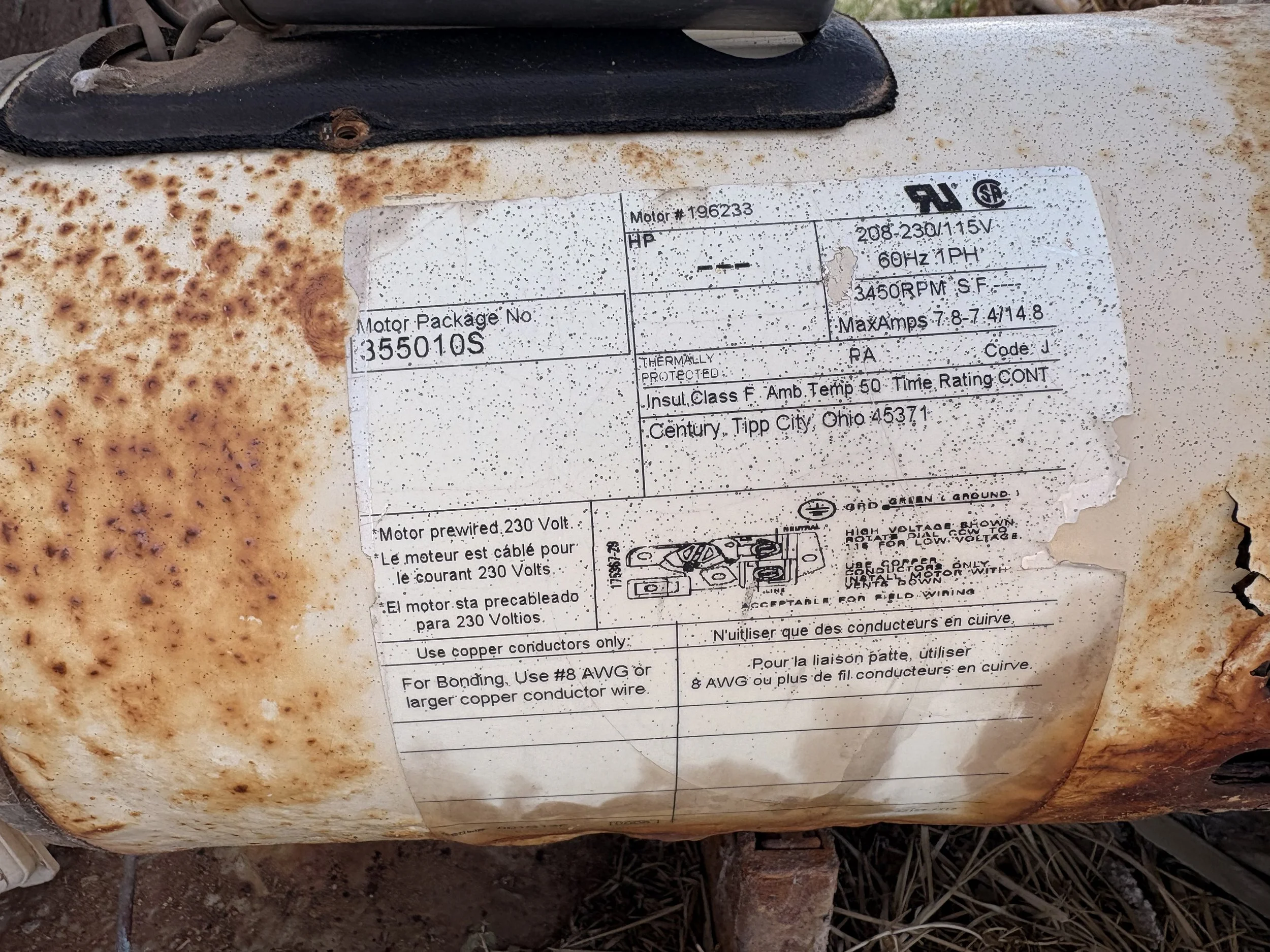 Close-up of a rusted air conditioning or electrical unit with a weathered label indicating model number 35501 S and specifications for motor and electrical details.