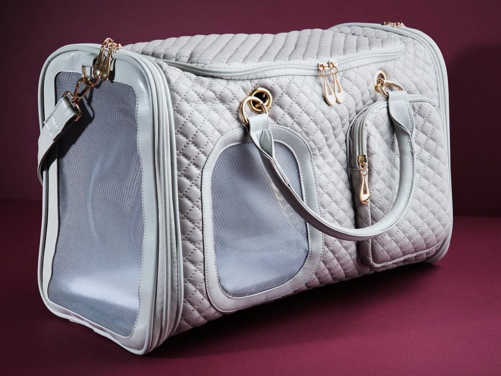 Grey soft-sided small animal tote bag on a purple background.